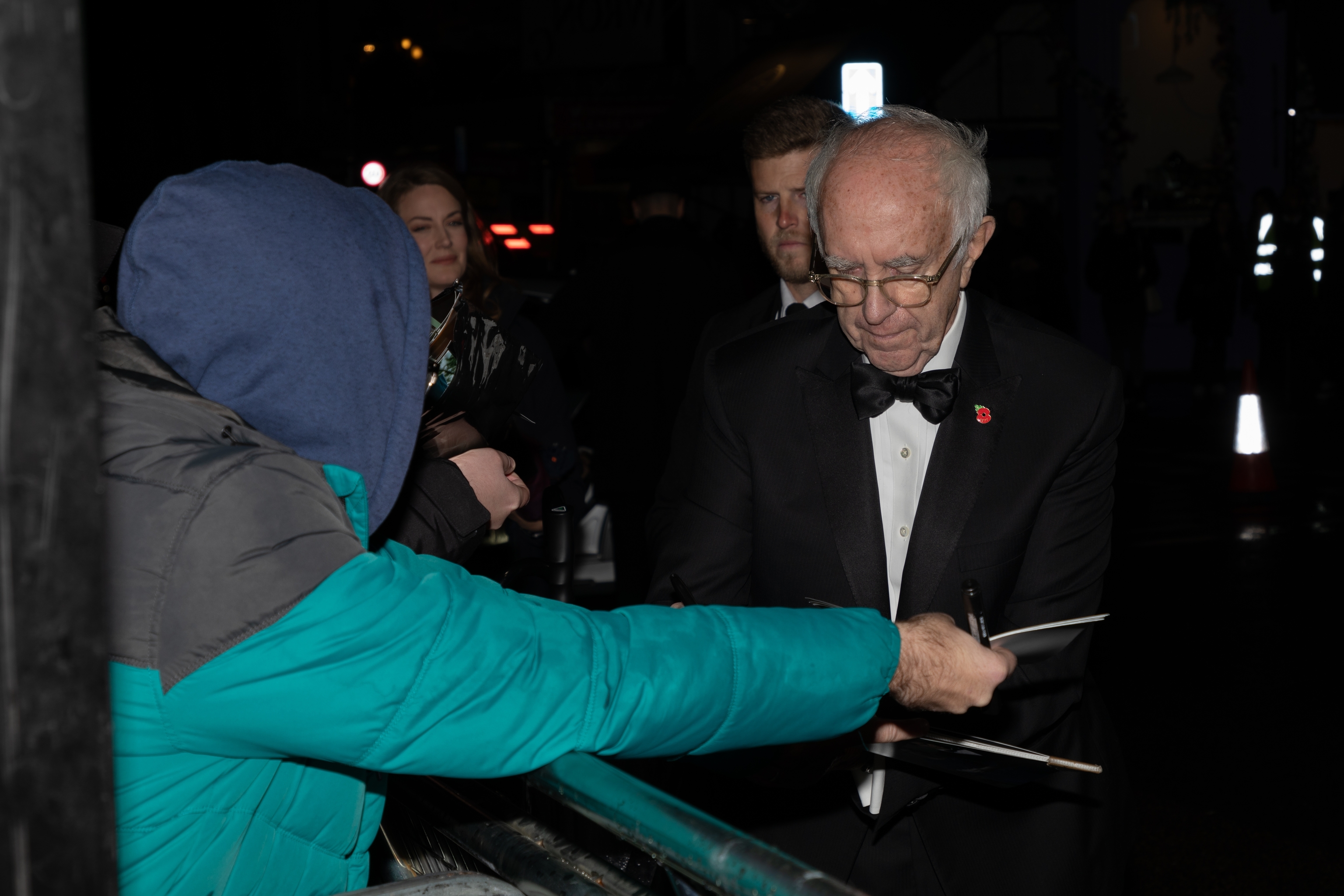 Sir Jonathan Pryce signs an autograph at 'The Crown' season five premiere.