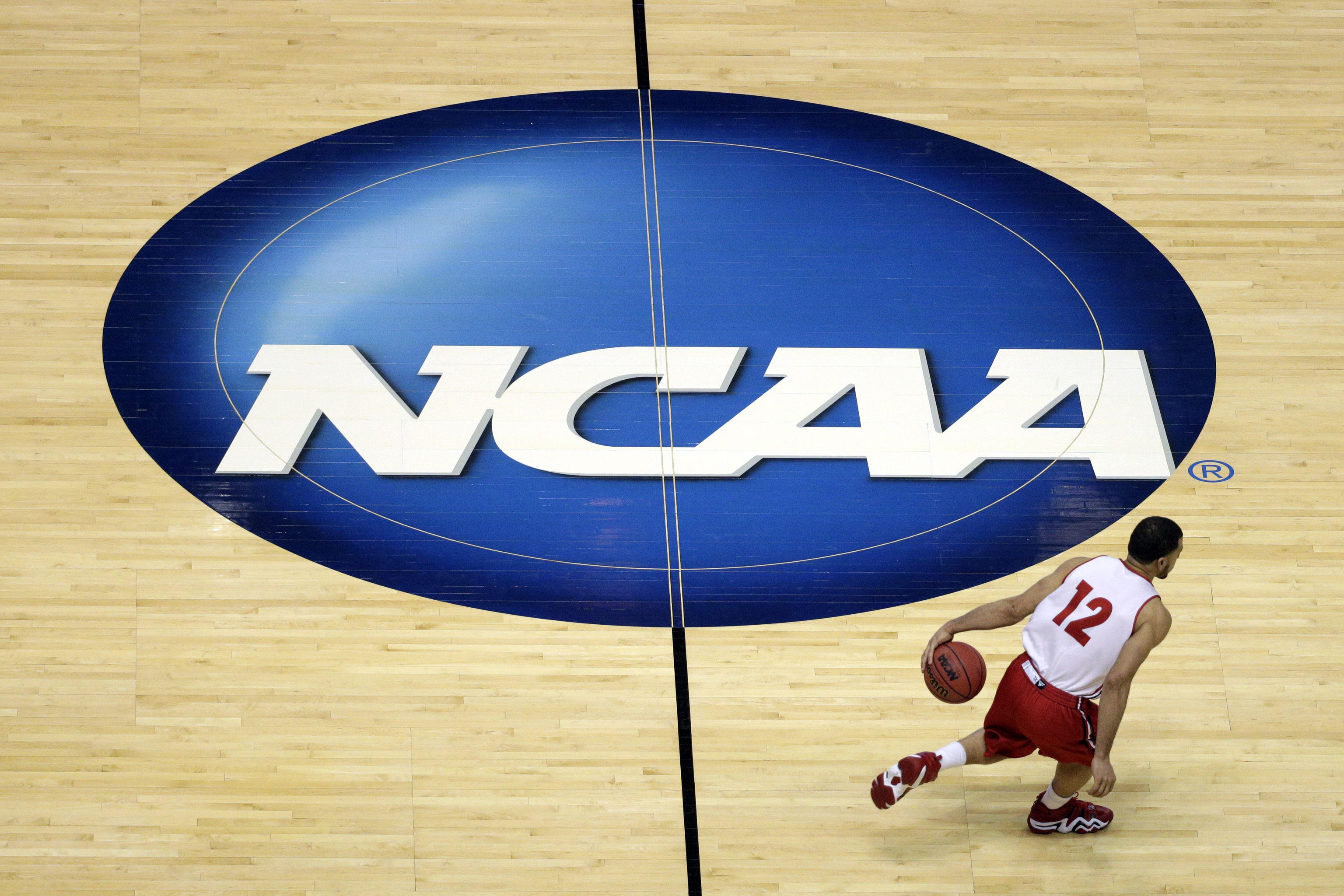 Wisconsin's Traevon Jackson dribbles past the NCAA logo.