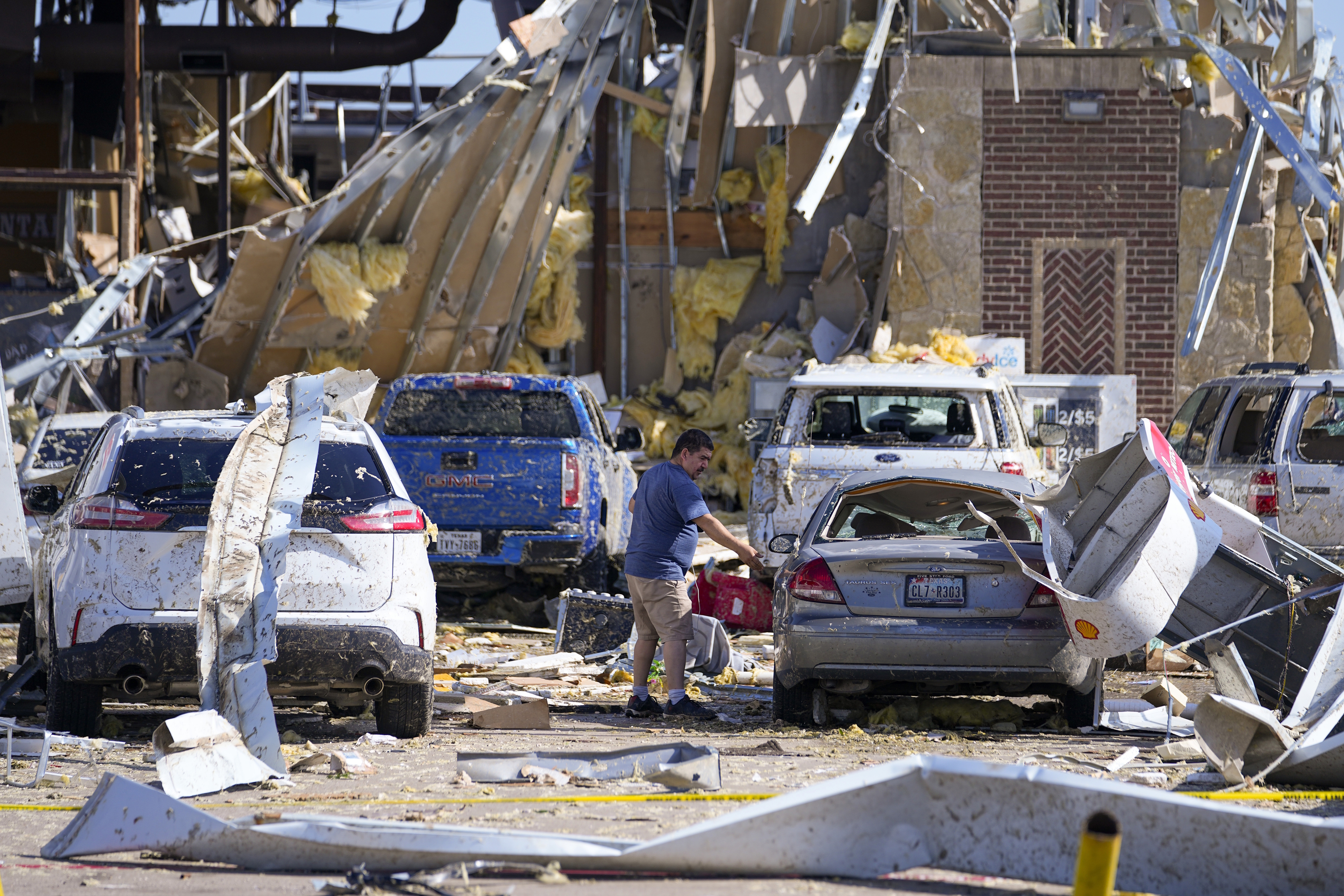 A man looks at a damaged car after a tornado hit in Texas.