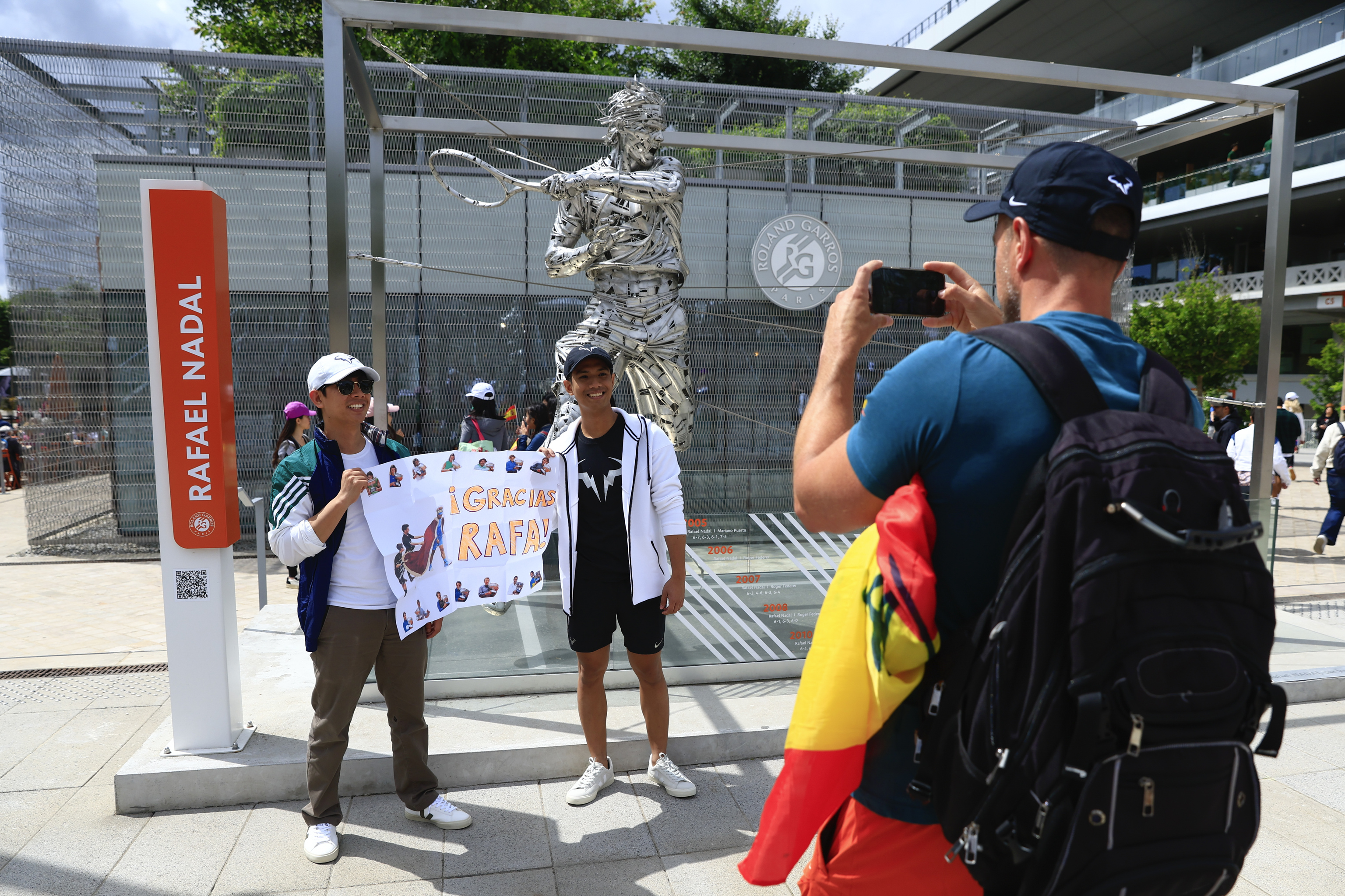 Fans of Spain's Rafael Nadal pose for pictures with his statue.