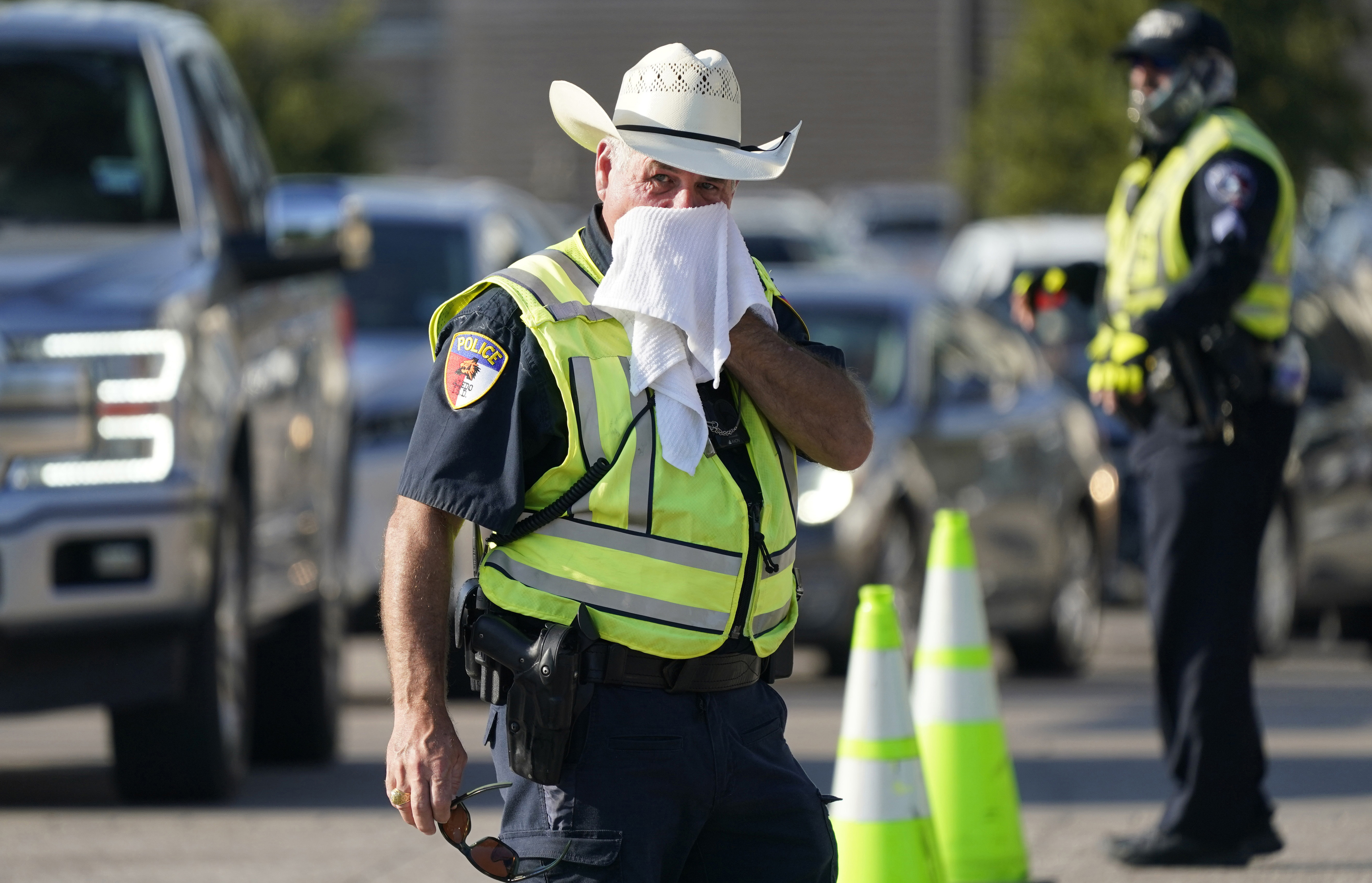 Police officer James Rhodes uses a wet towel to cool off as he directs traffic after a sporting event in Arlington, Texas