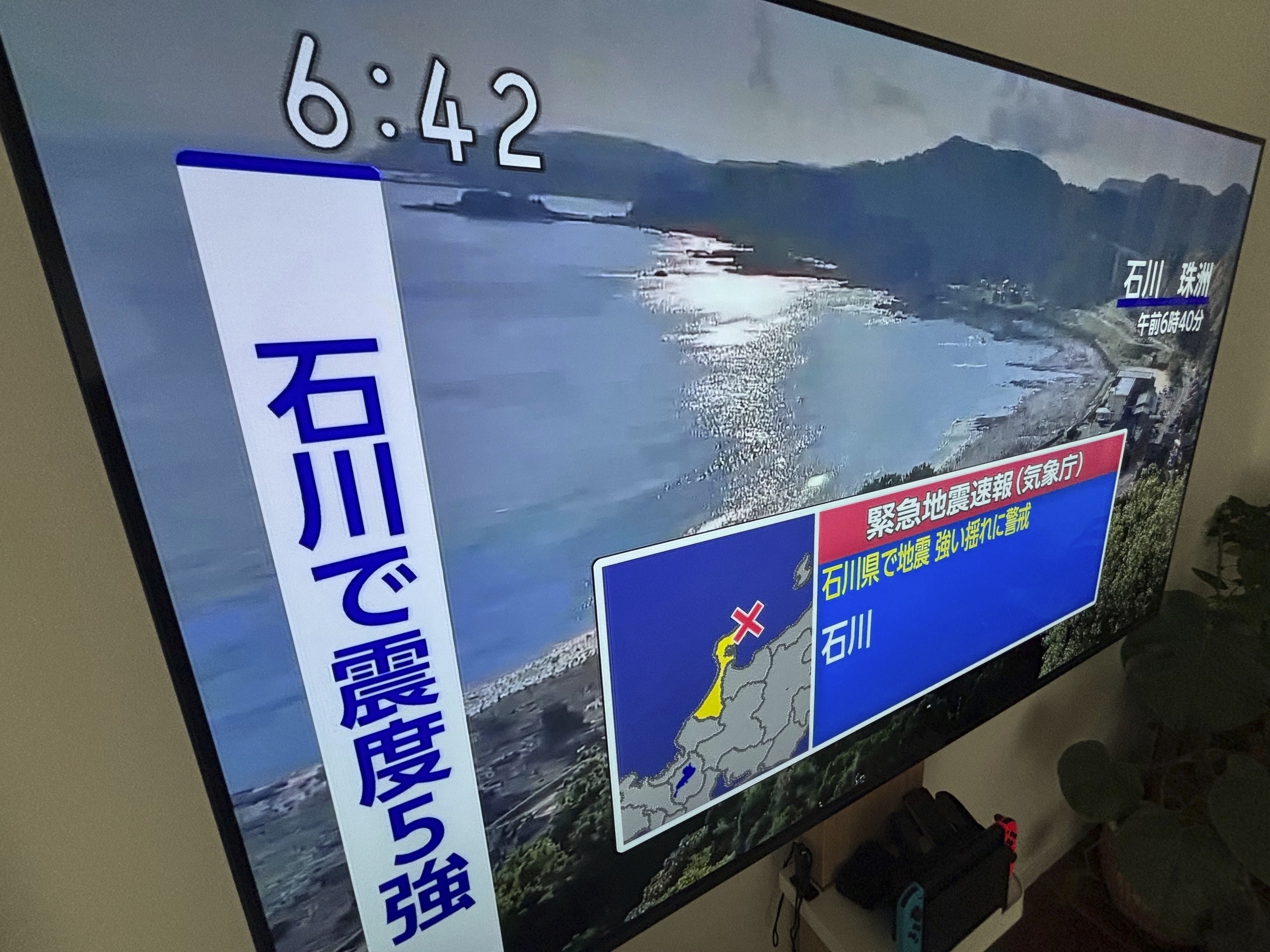 An emergency earthquake alert for Ishikawa Prefecture area is shown on a TV.