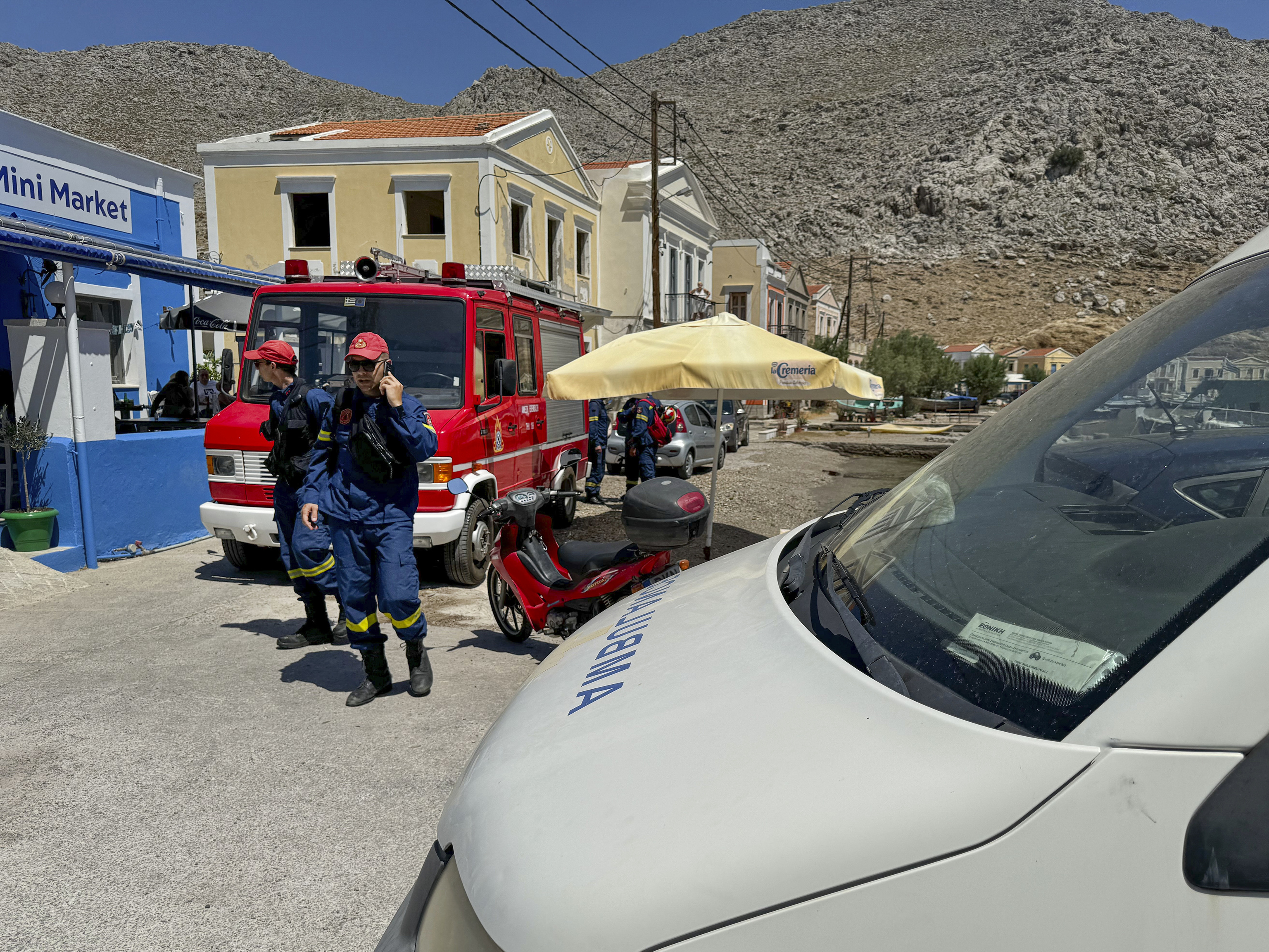 Greek Fire brigade personnel walk on a beachfront of Symi island.