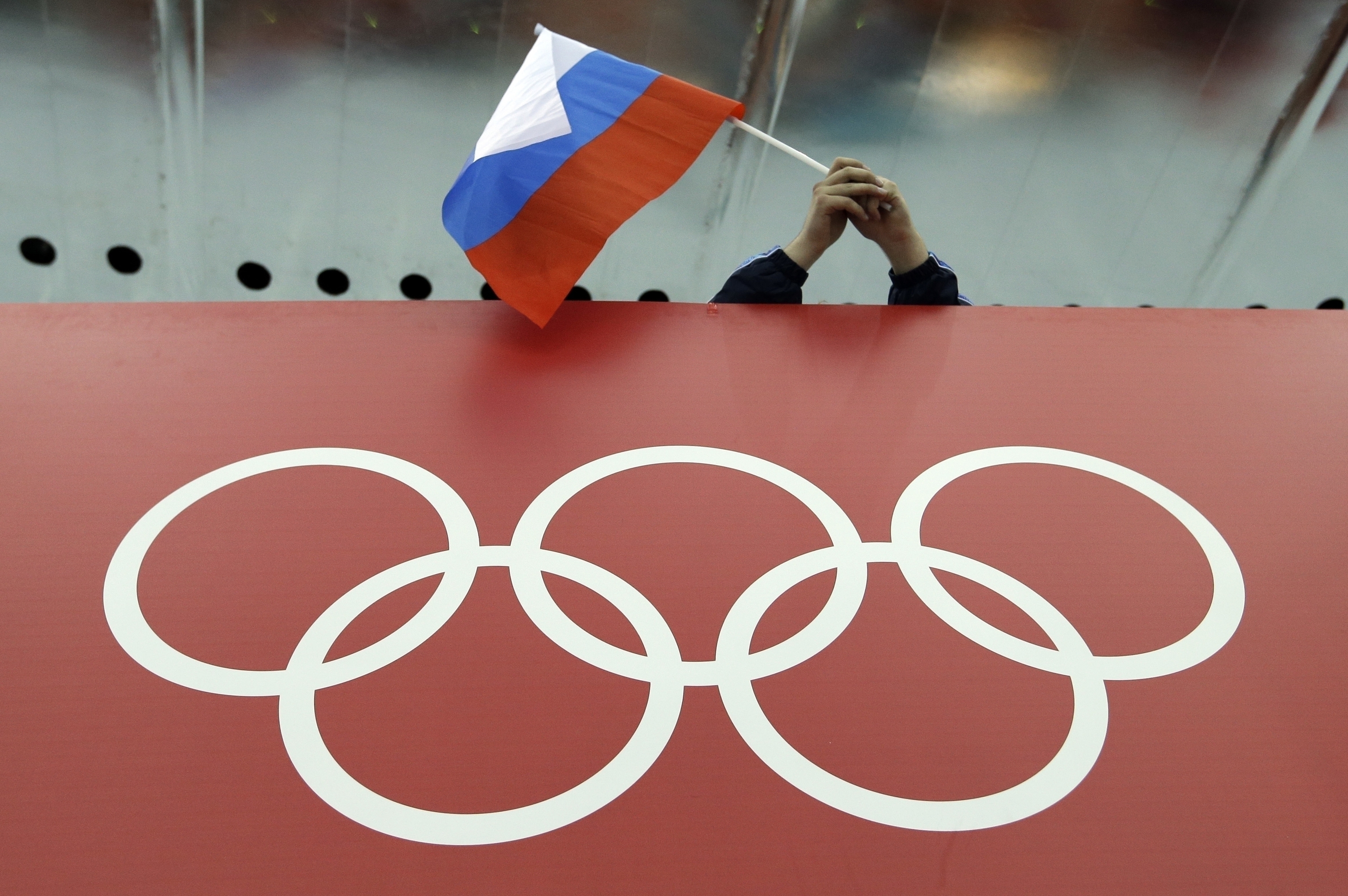 A Russian flag is held above the Olympic Rings at Adler Arena Skating Center during the Winter Olympics.