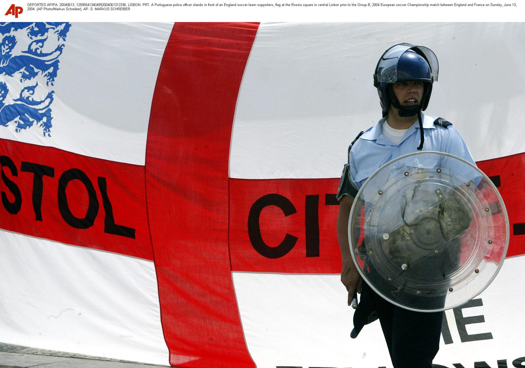 A Portuguese police officer stands in front of an England soccer team supporters.