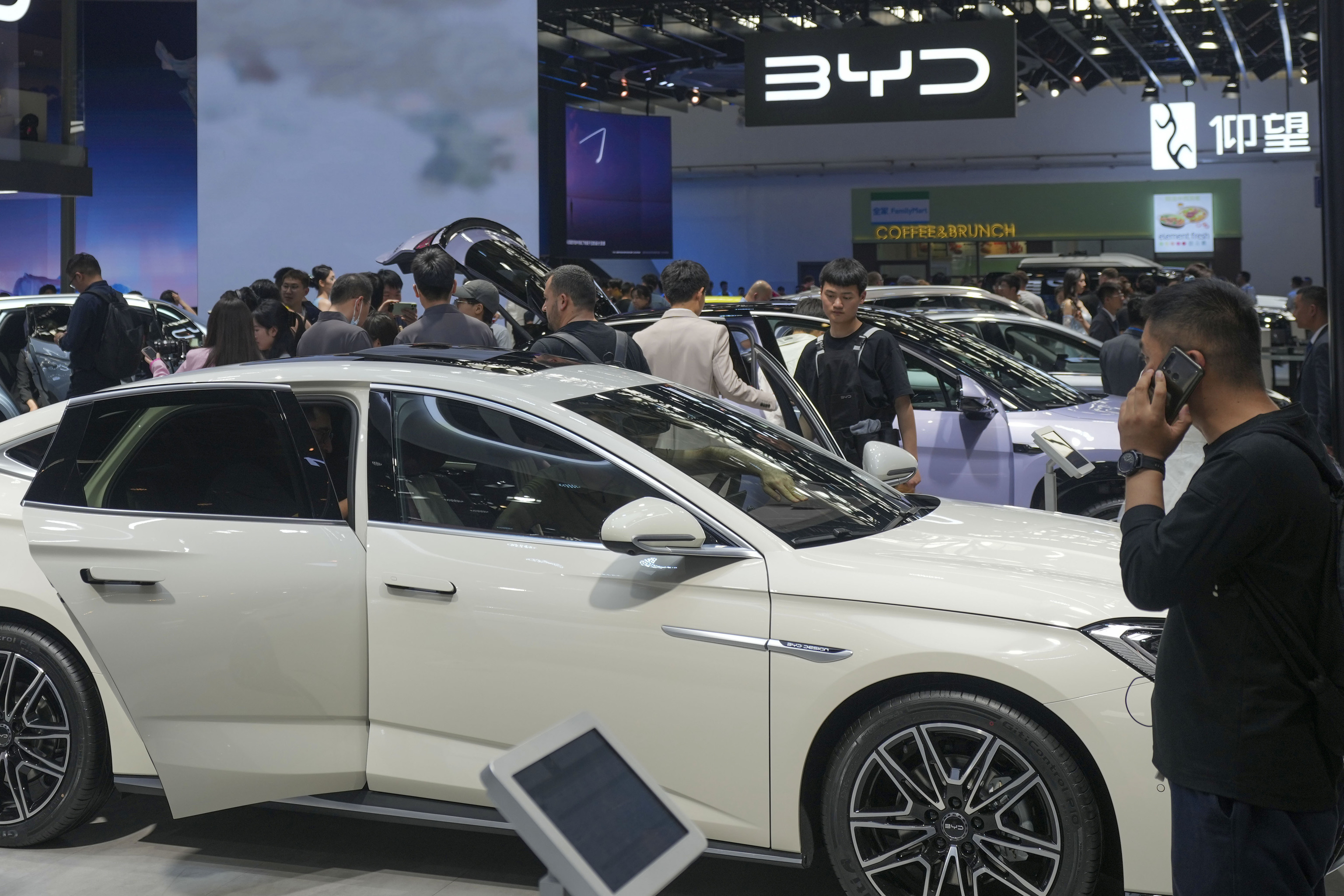 Visitors look at cars at the BYD booth during the China Auto Show in Beijing, China,