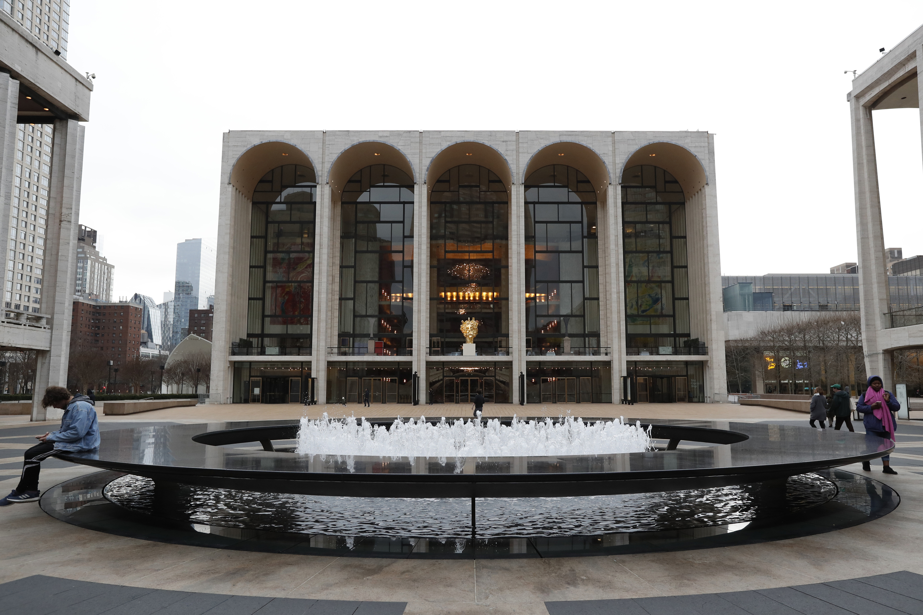 eople appear in Josie Robertson Plaza in front of The Metropolitan Opera house at Lincoln Center in New York