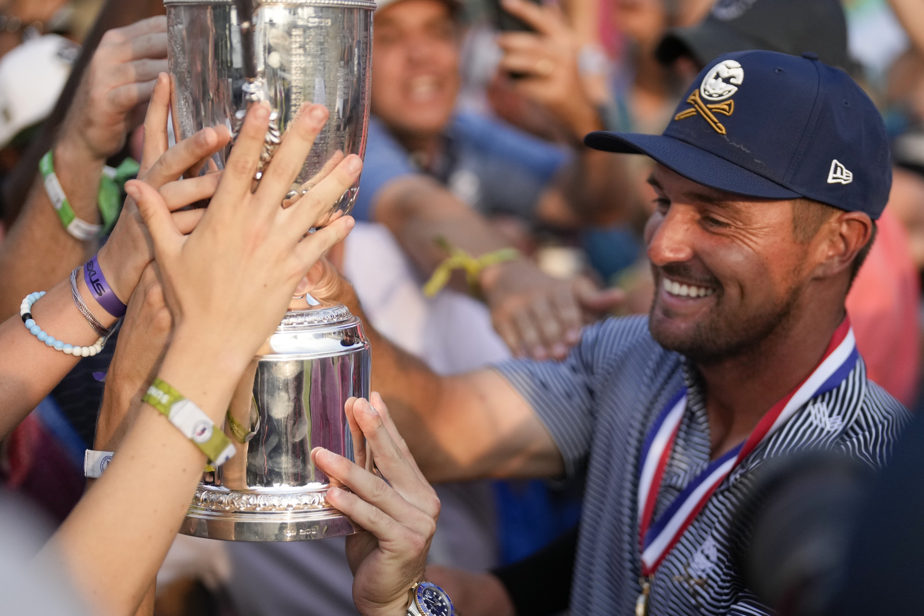 DeChambeau shows the trophy to fans.