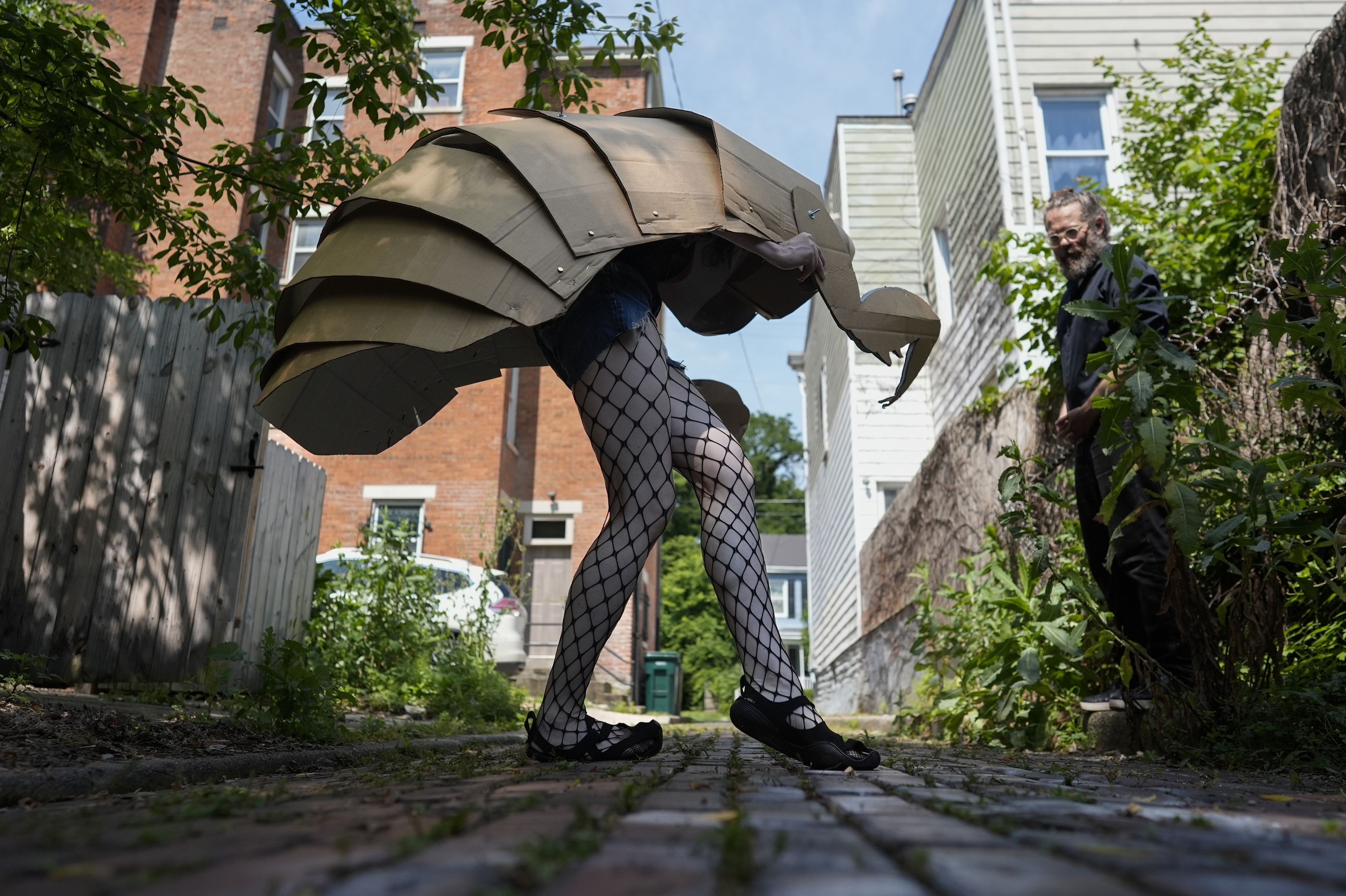 Renee Martin performs her cicada striptease in fishnet stockings and a cicada nymph puppet costume in a Cincinnati ally