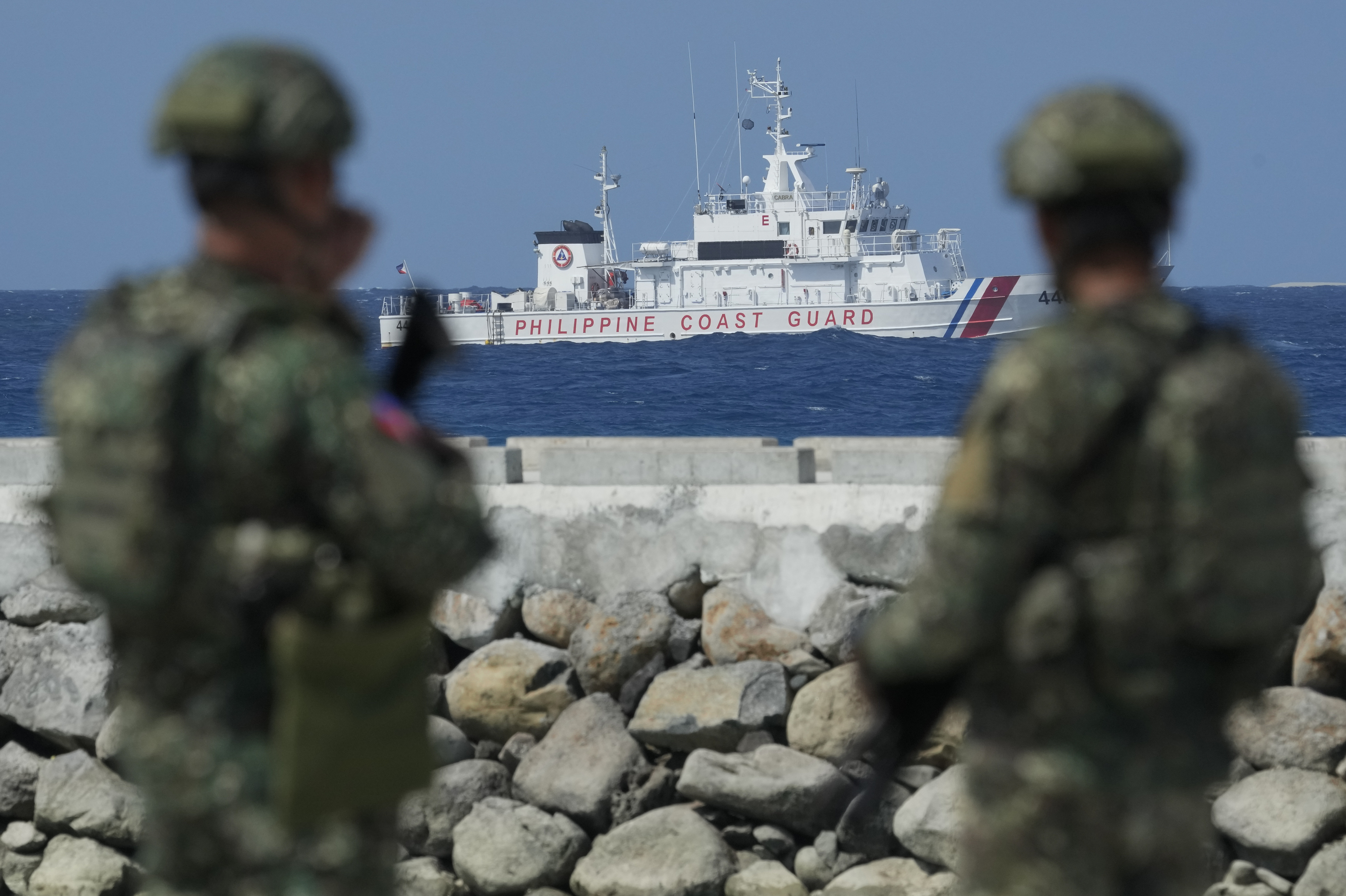 Philippine troops watch a Philippine coast guard ship as they secure an area at the Philippine-occupied Thitu island, locally called Pag-asa island