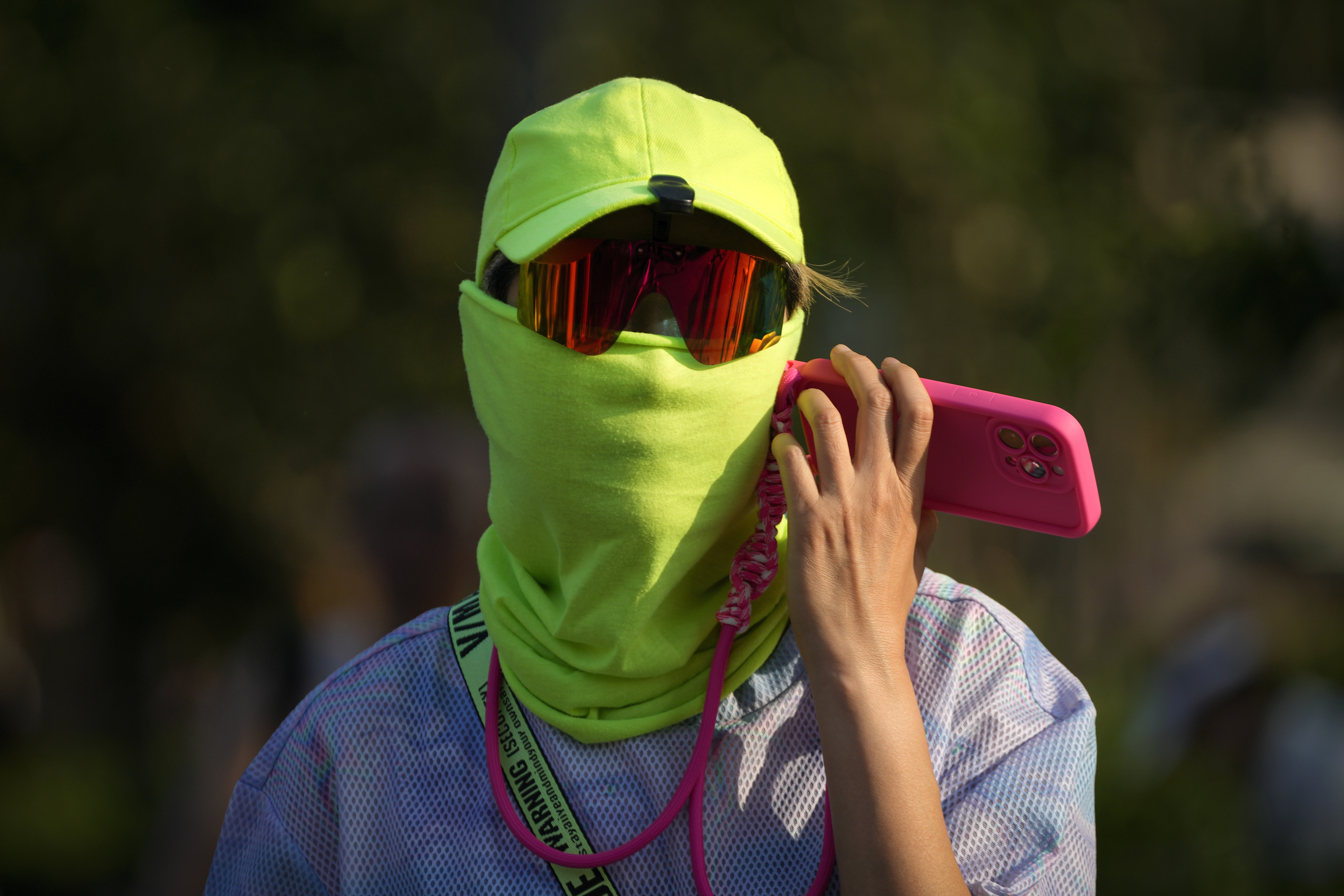 A man wearing a face cover uses his mobile phone as he walks during an unseasonably hot day in Beijing