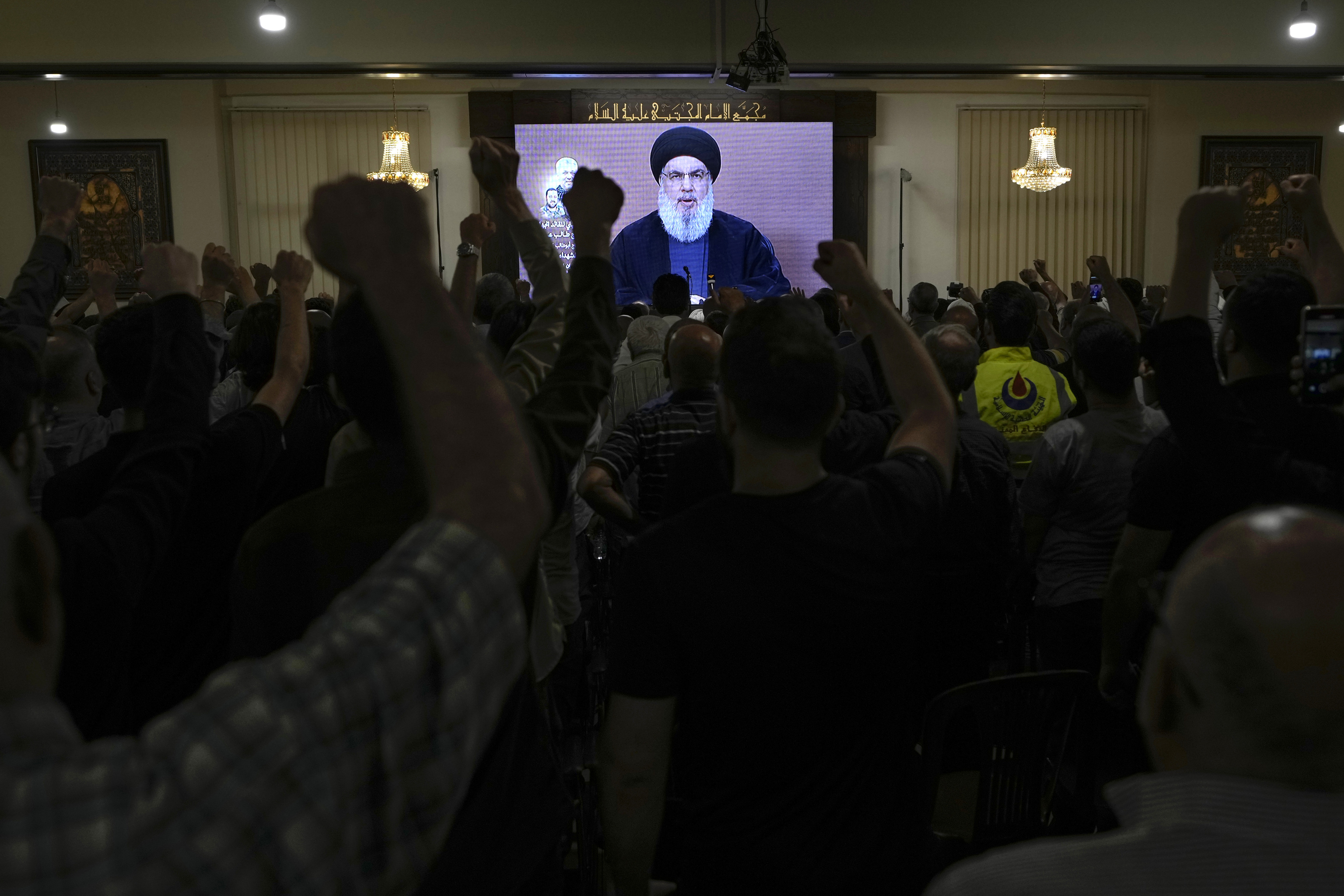 Hezbollah supporters raise their fists and cheer as they watch a speech given by Hezbollah leader Sayyed Hassan Nasrallah.