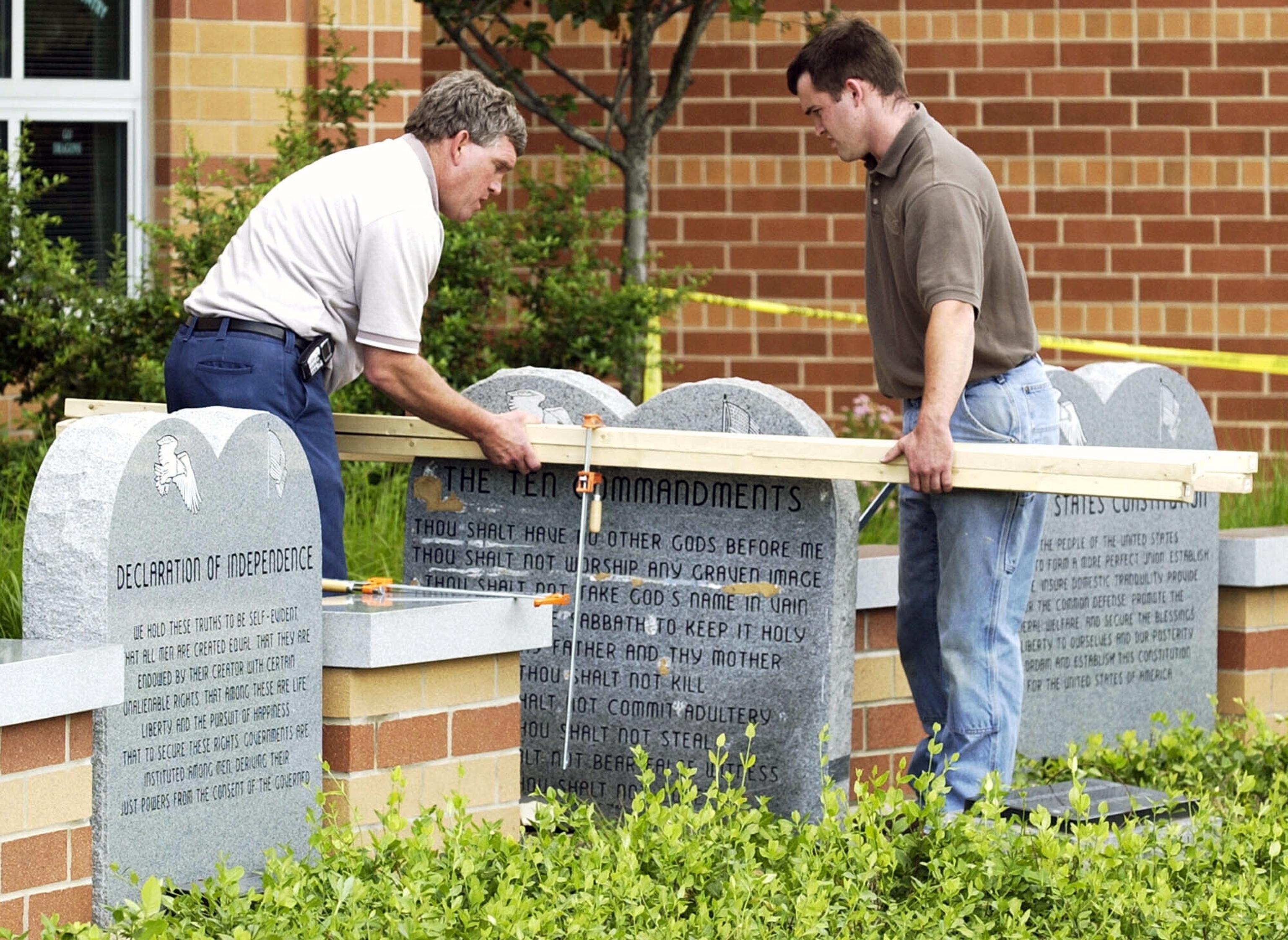 Workers remove a monument bearing the Ten Commandments outside West Union High School.