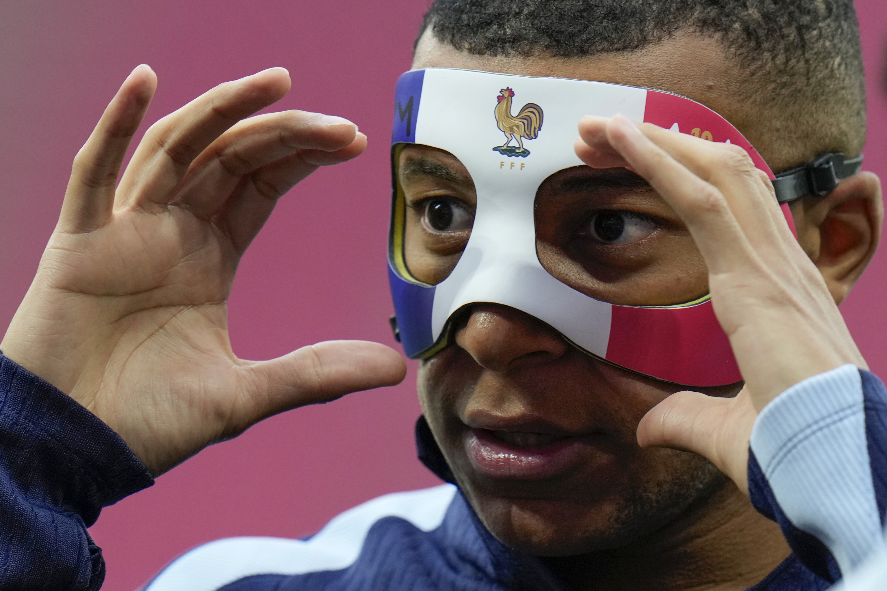 Mbappe adjusts his face mask during a training session.