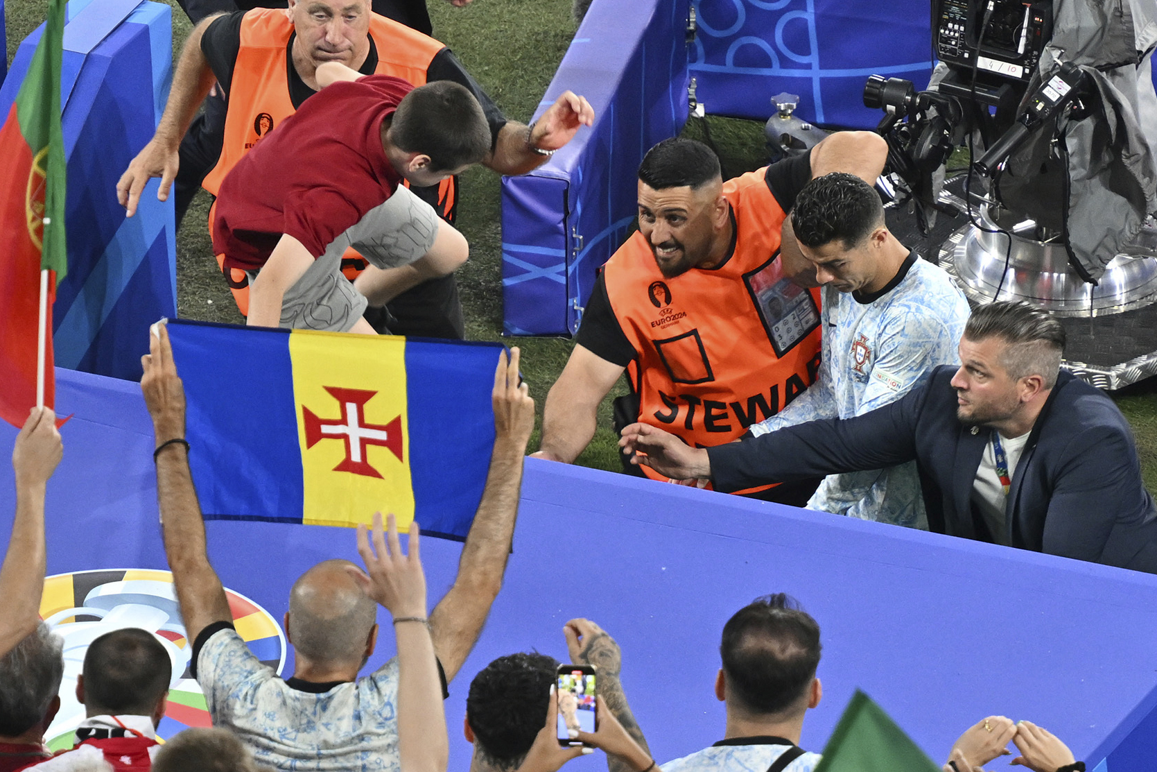 A boy crosses the barriers as Portugal's Cristiano Ronaldo, rear second right, leaves the pitch