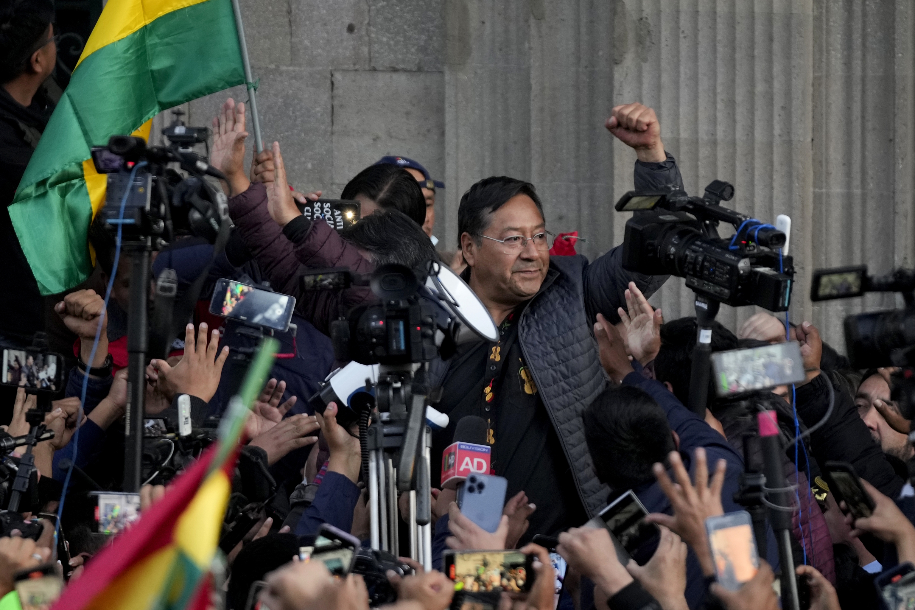 Luis Arce raises a clenched fist surrounded by supporters.