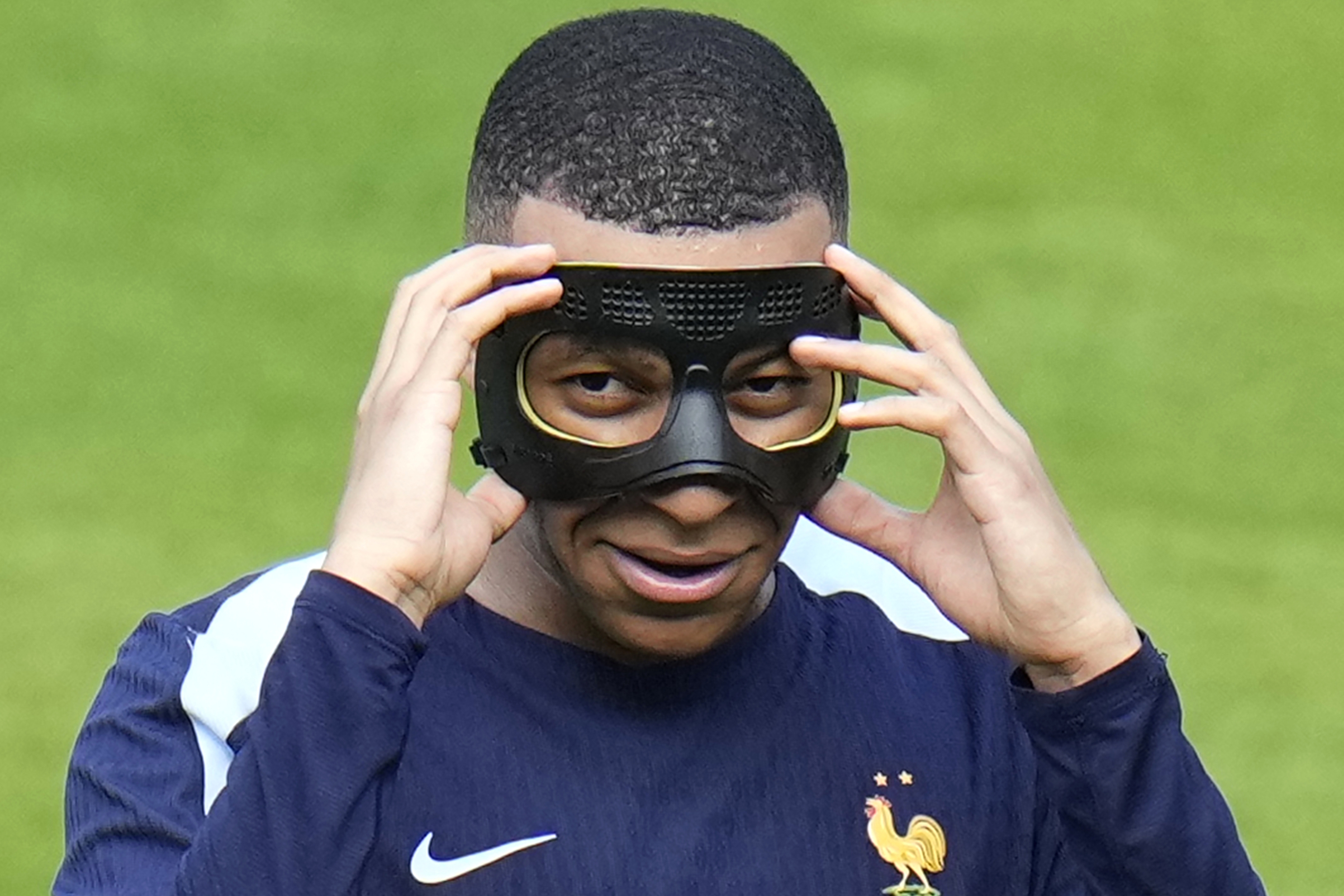 Mbappe gestures as he adjusts his face mask.