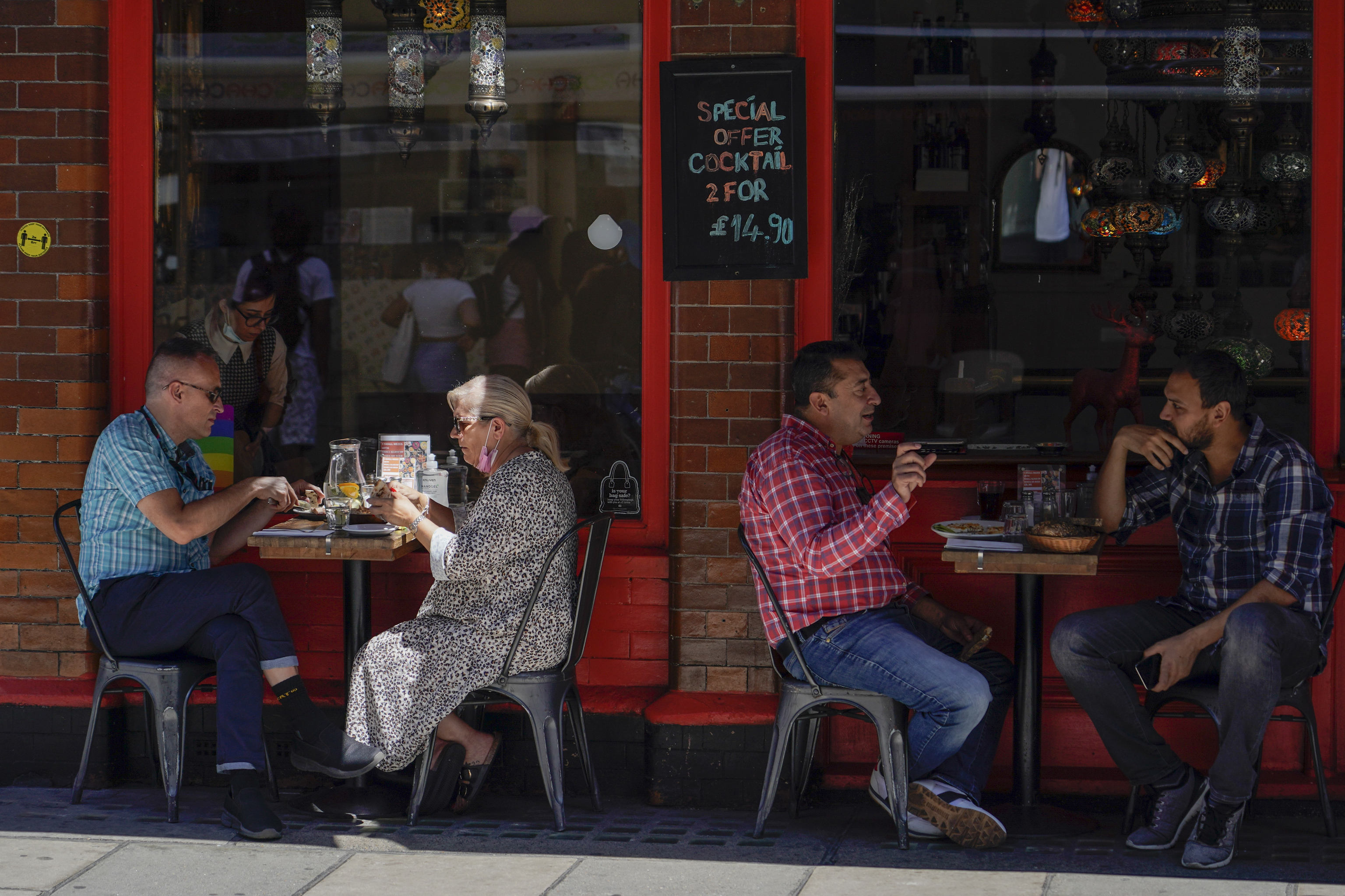 people sit at outdoor tables at a restaurant in Soho, in London