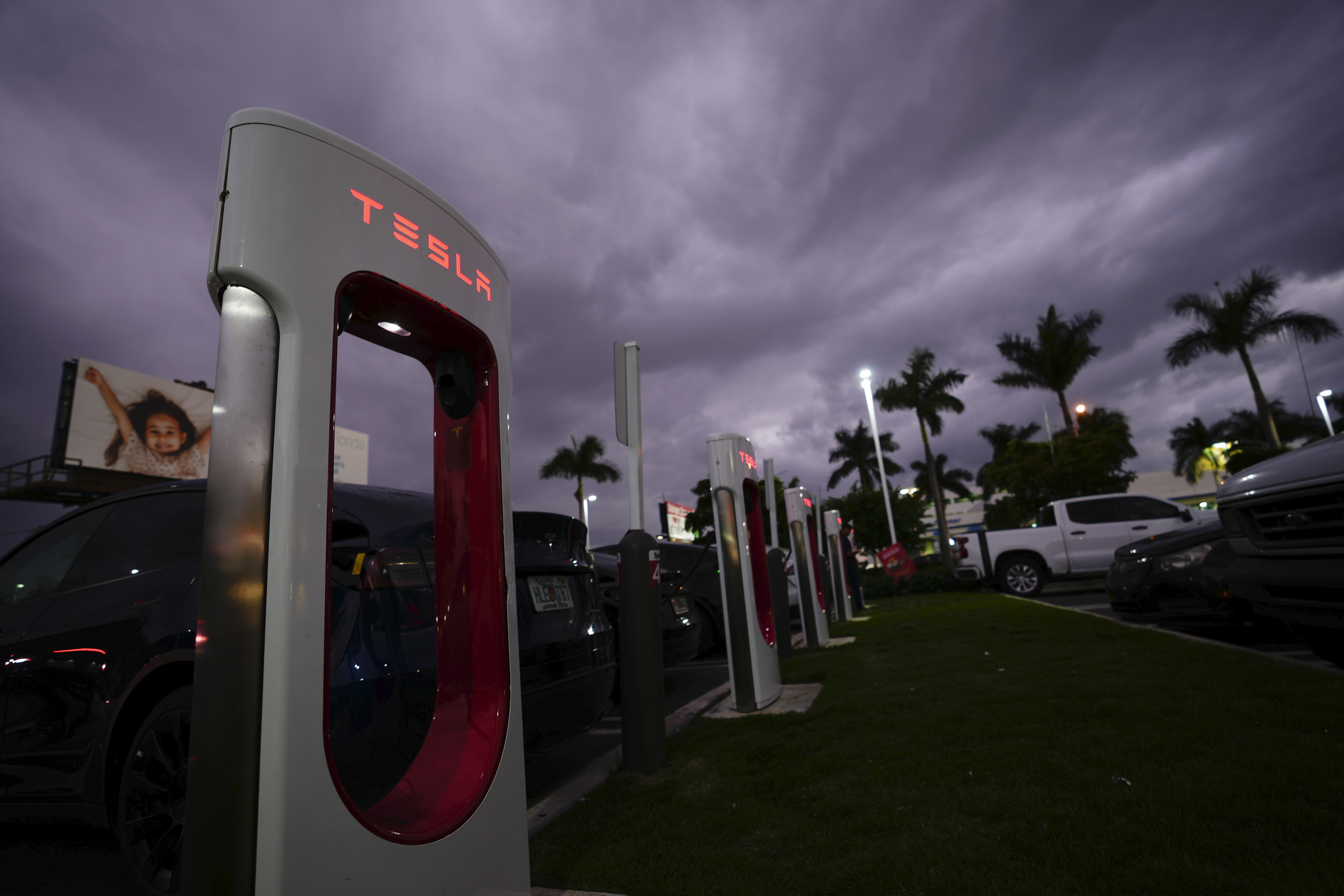 Tesla drivers charge their cars at a Supercharger station.