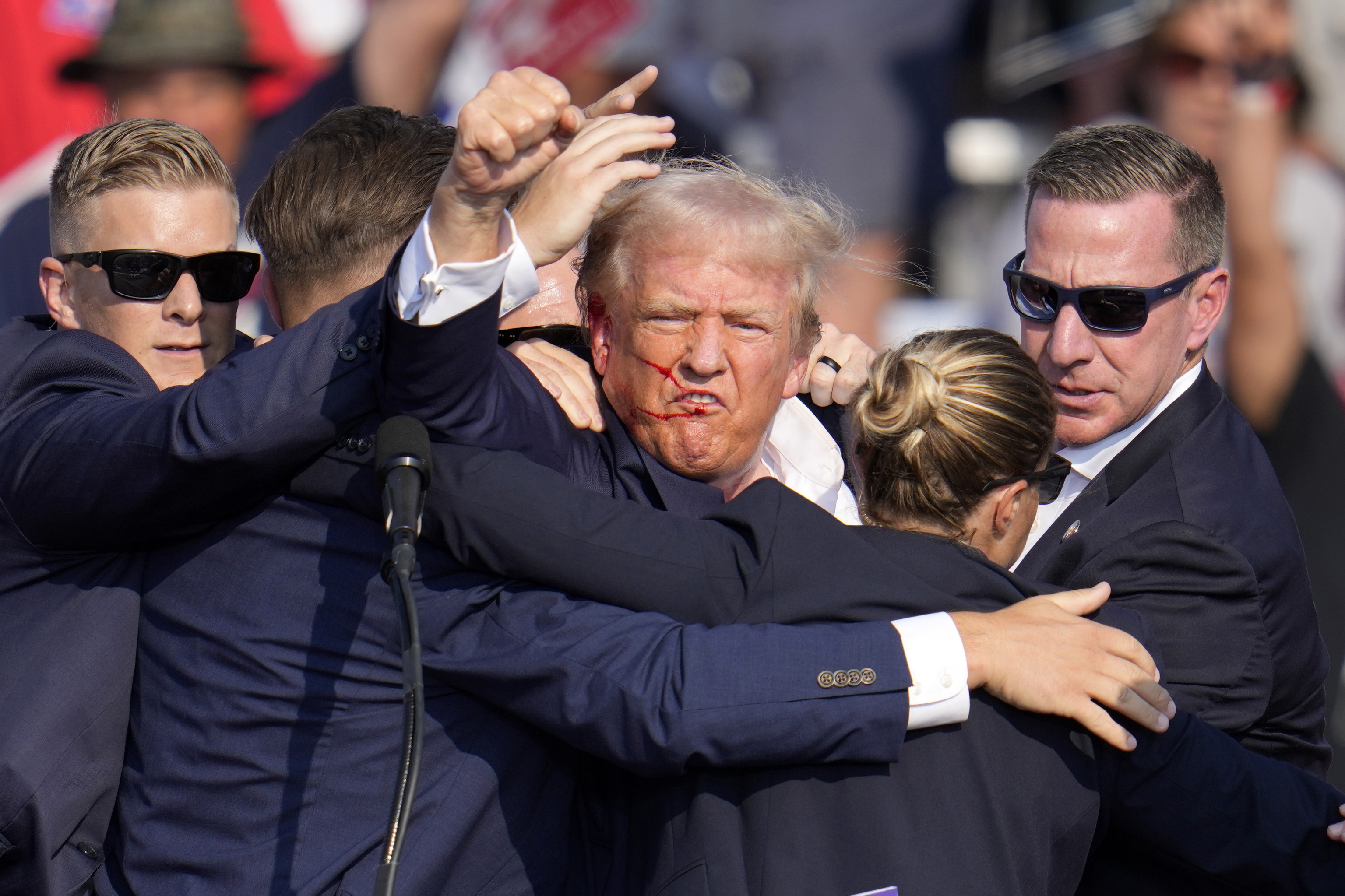 Republican presidential candidate former President Donald Trump pumps his fist as he is helped off the stage at a campaign event in Butler.