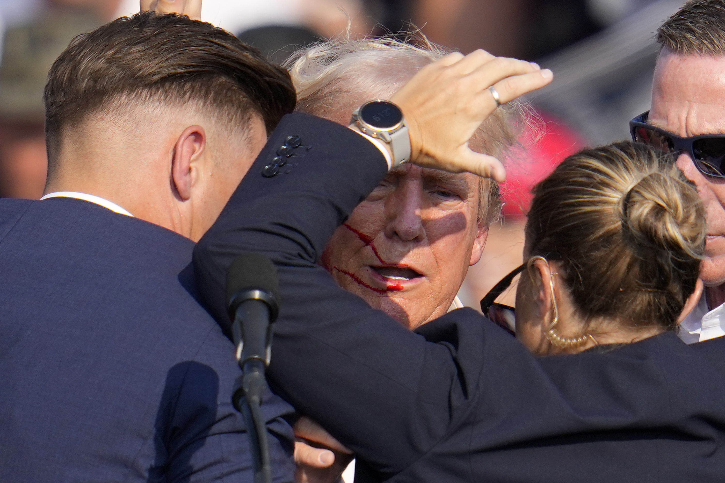 Republican presidential candidate former President Donald Trump is helped off the stage by U.S. Secret Service agents.