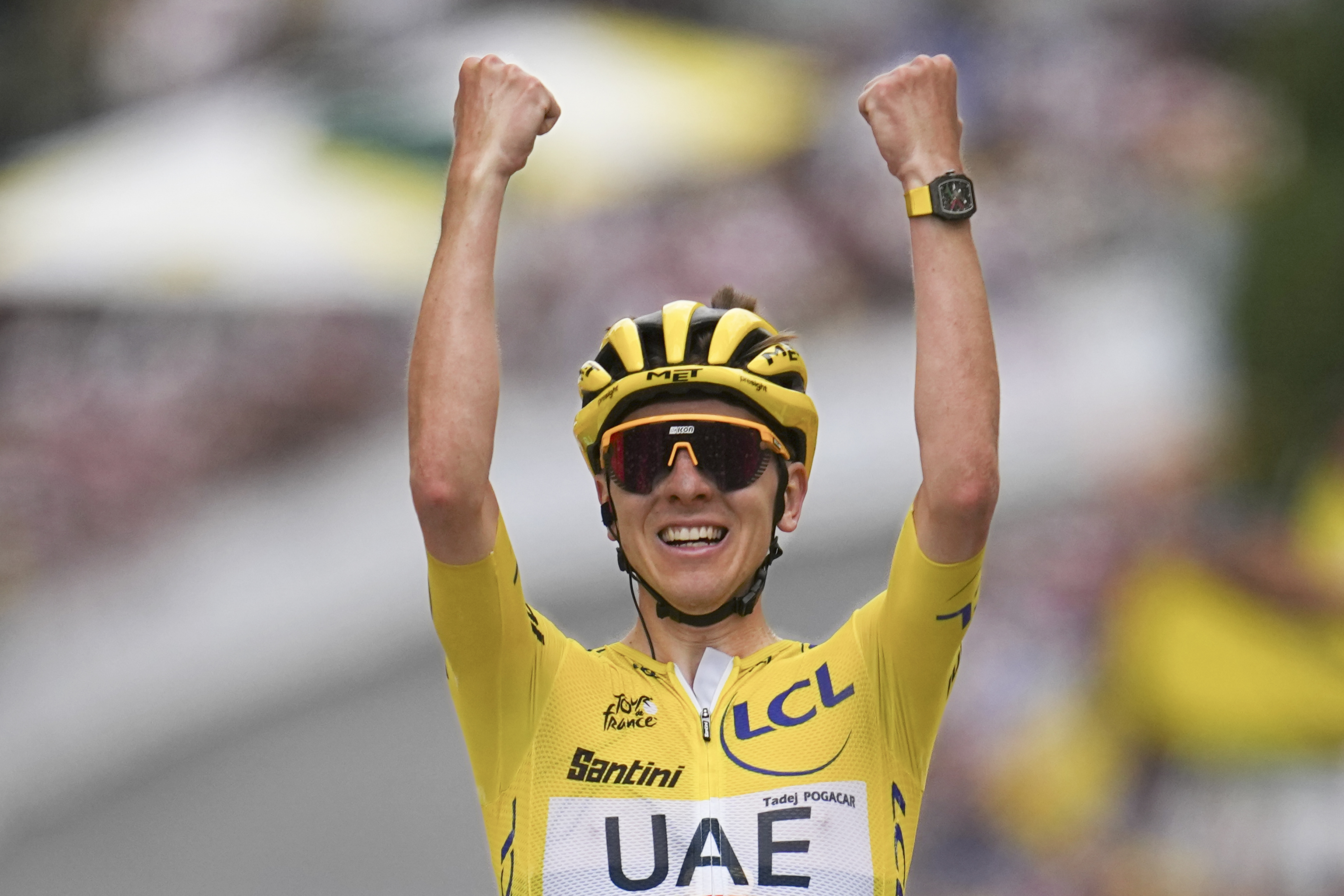 Slovenia's Tadej Pogacar, wearing the overall leader's yellow jersey, celebrates as he crosses the finish line to win the nineteenth stage of the Tour de France.