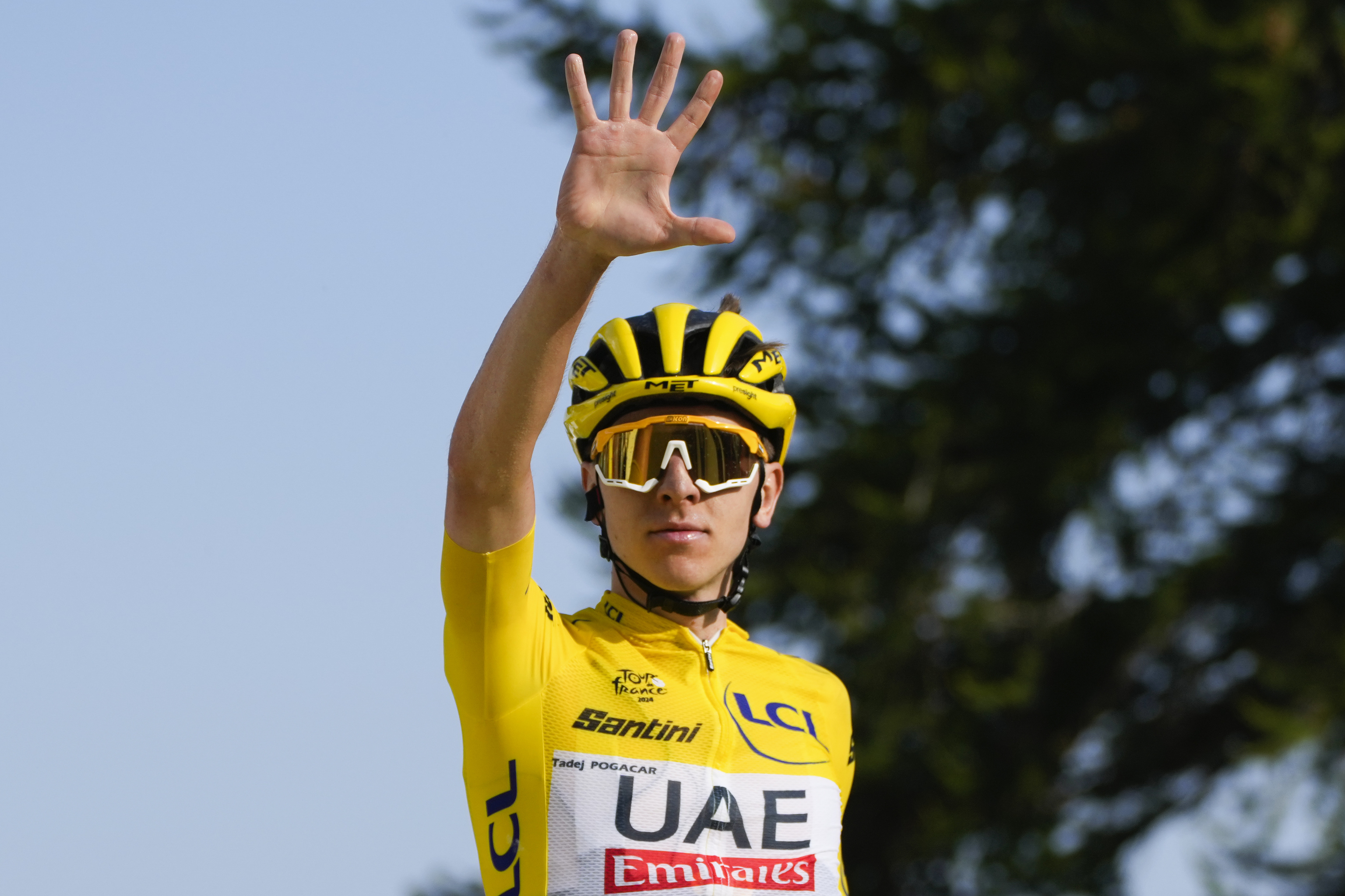 Slovenia's Tadej Pogacar, wearing the overall leader's yellow jersey, flashes five fingers for his fifth stage victory.