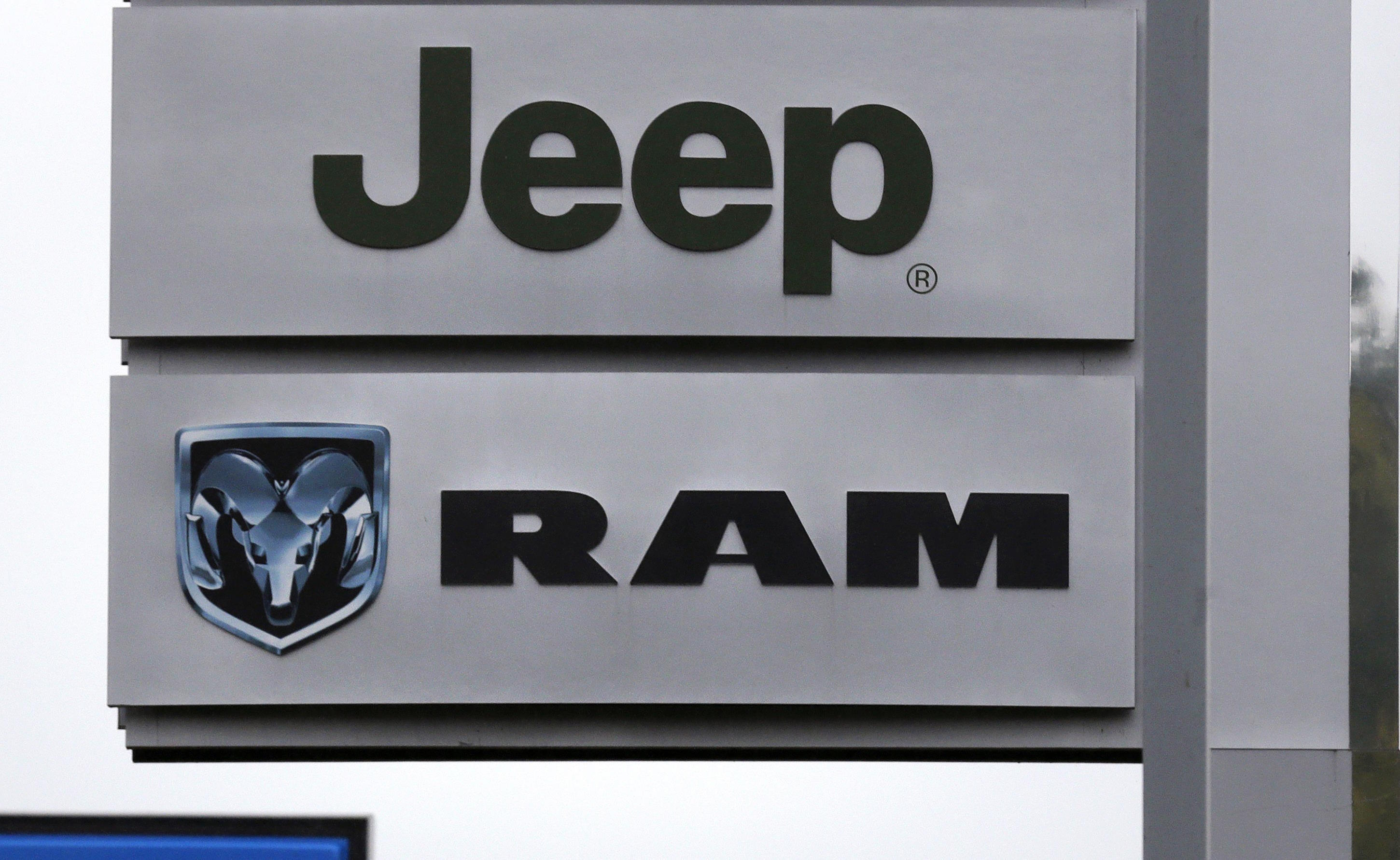 Jeep and Dodge Ram logos on signs at a dealership.