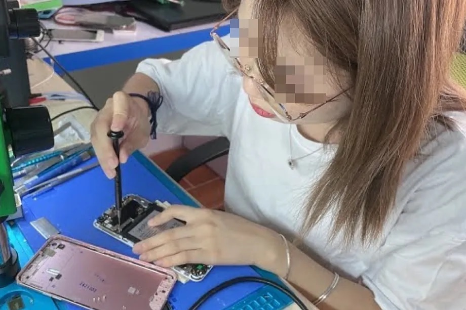 A Chinese woman repairs a cell phone.