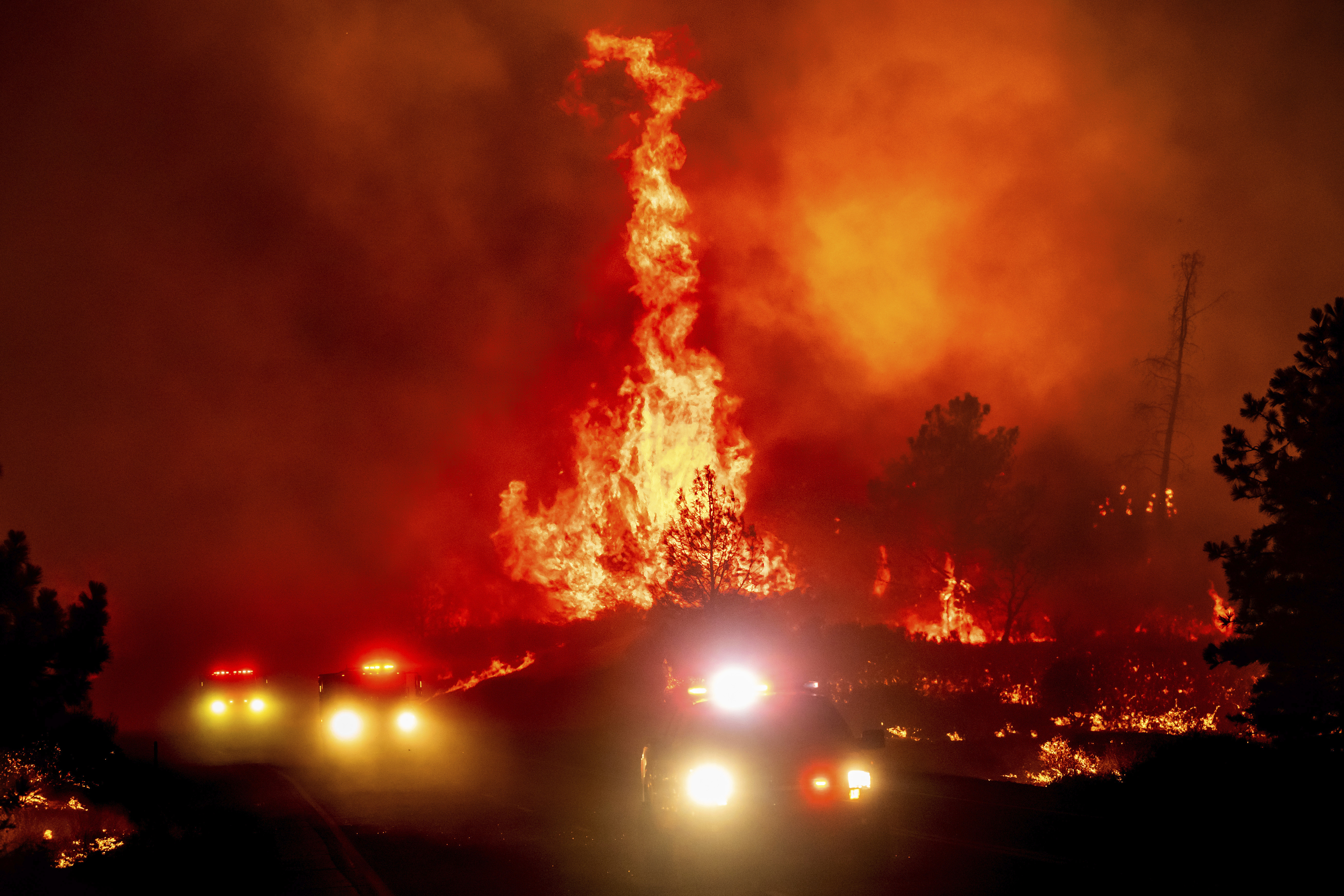 Flames leap above fire vehicles as the Park Fire jumps Highway 36 near Paynes Creek.