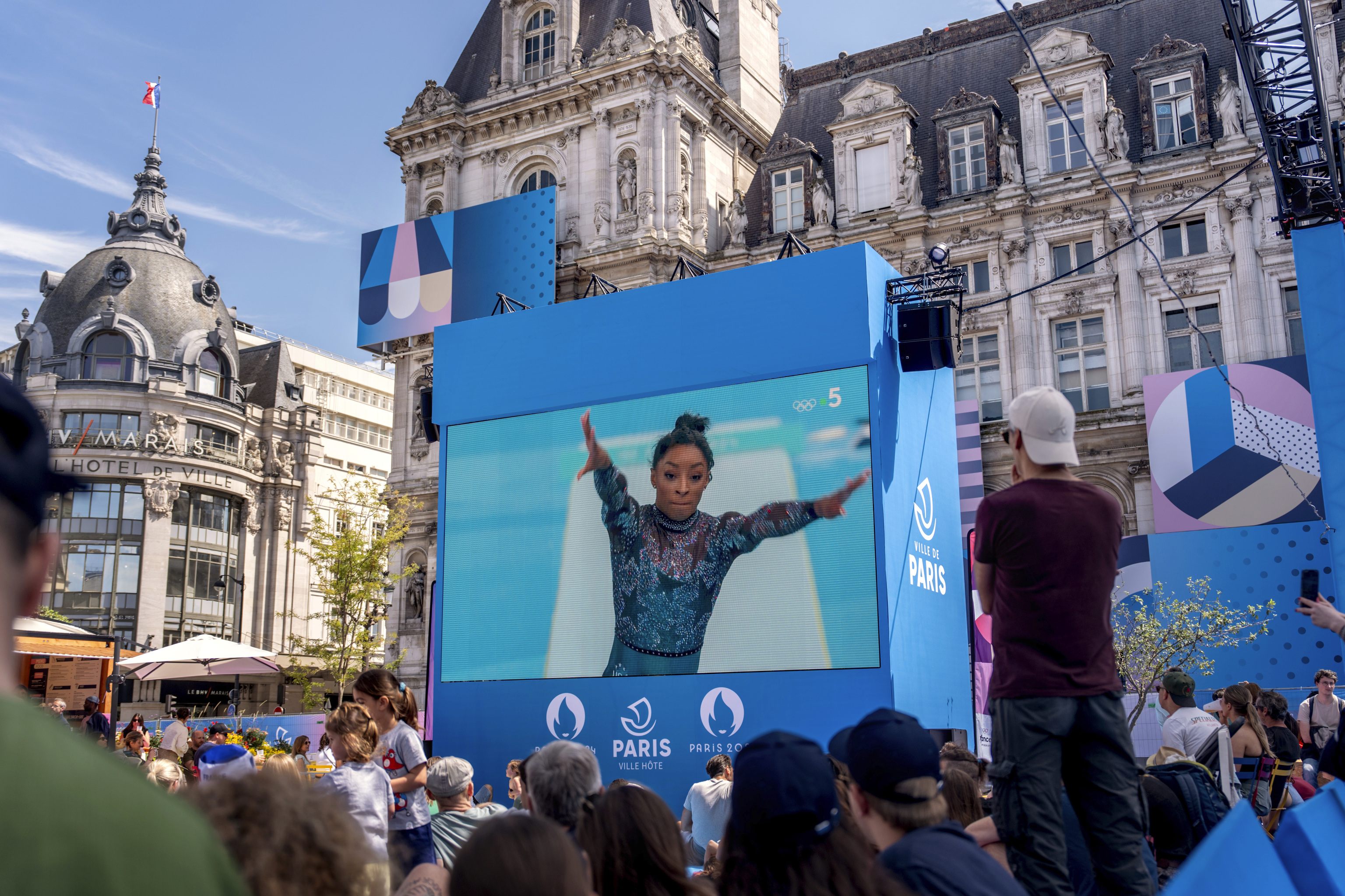 Spectators watch from a fan zone set up at the Hotel de Ville, the city hall, as Simone Biles, of the United States, performs on the vault .