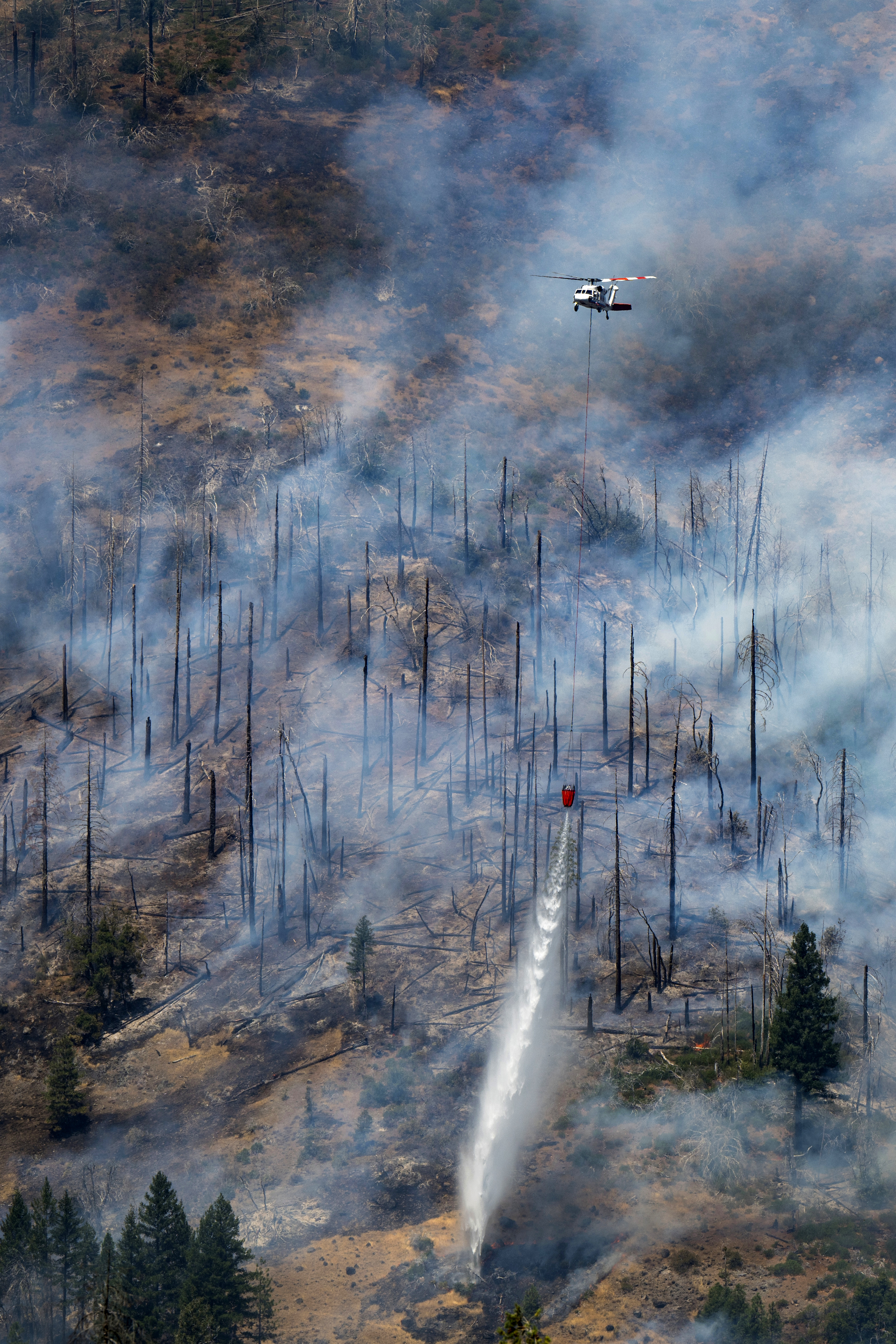 A helicopter drops water on the Park Fire near Butte Meadows, California.