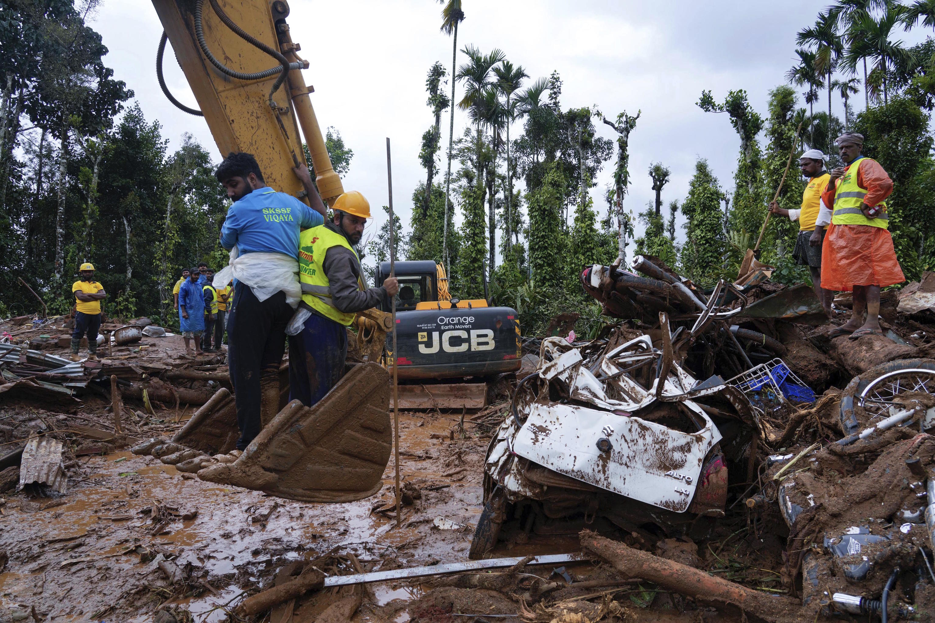 Rescuers use machinery to sift through debris.