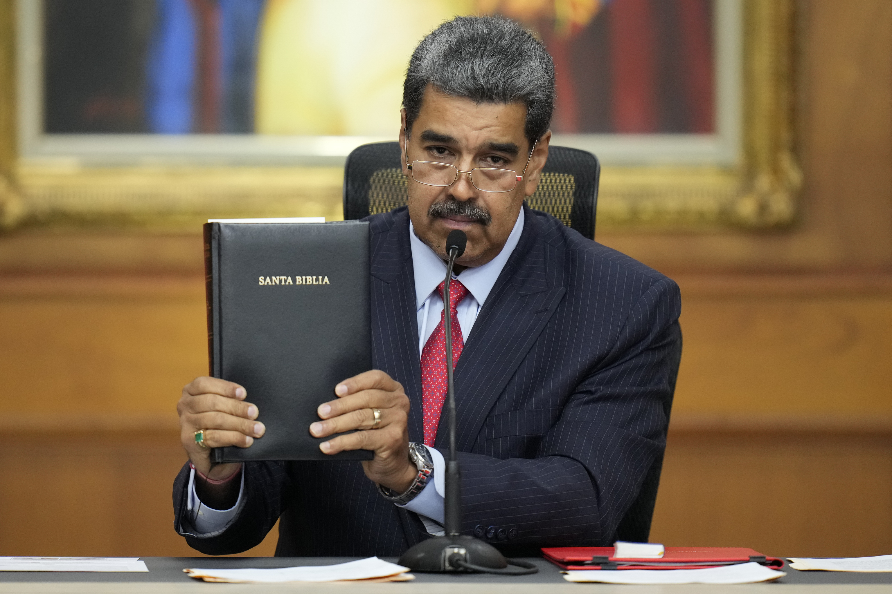 Venezuelan President Nicolas Maduro holds a Bible during his news conference.