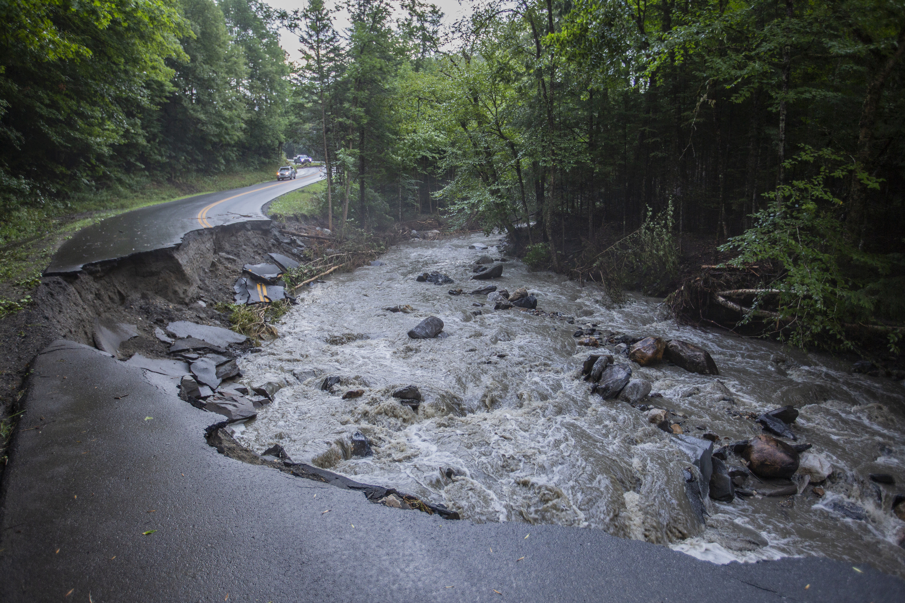 A river flows past a damaged road in the aftermath of flash floods in Lyndonville.