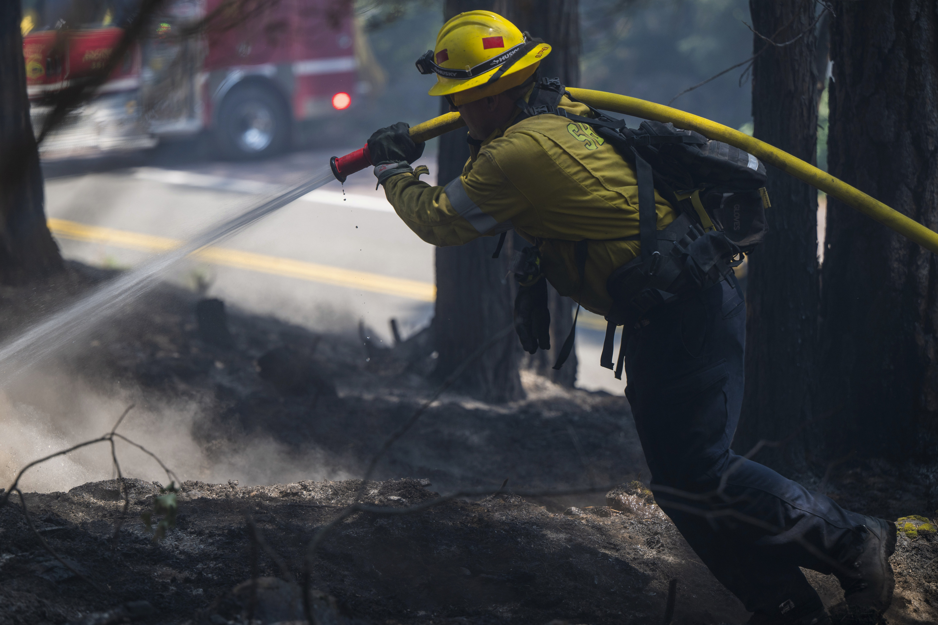 A firefighter sprays water on hot spots from the Park Fire.