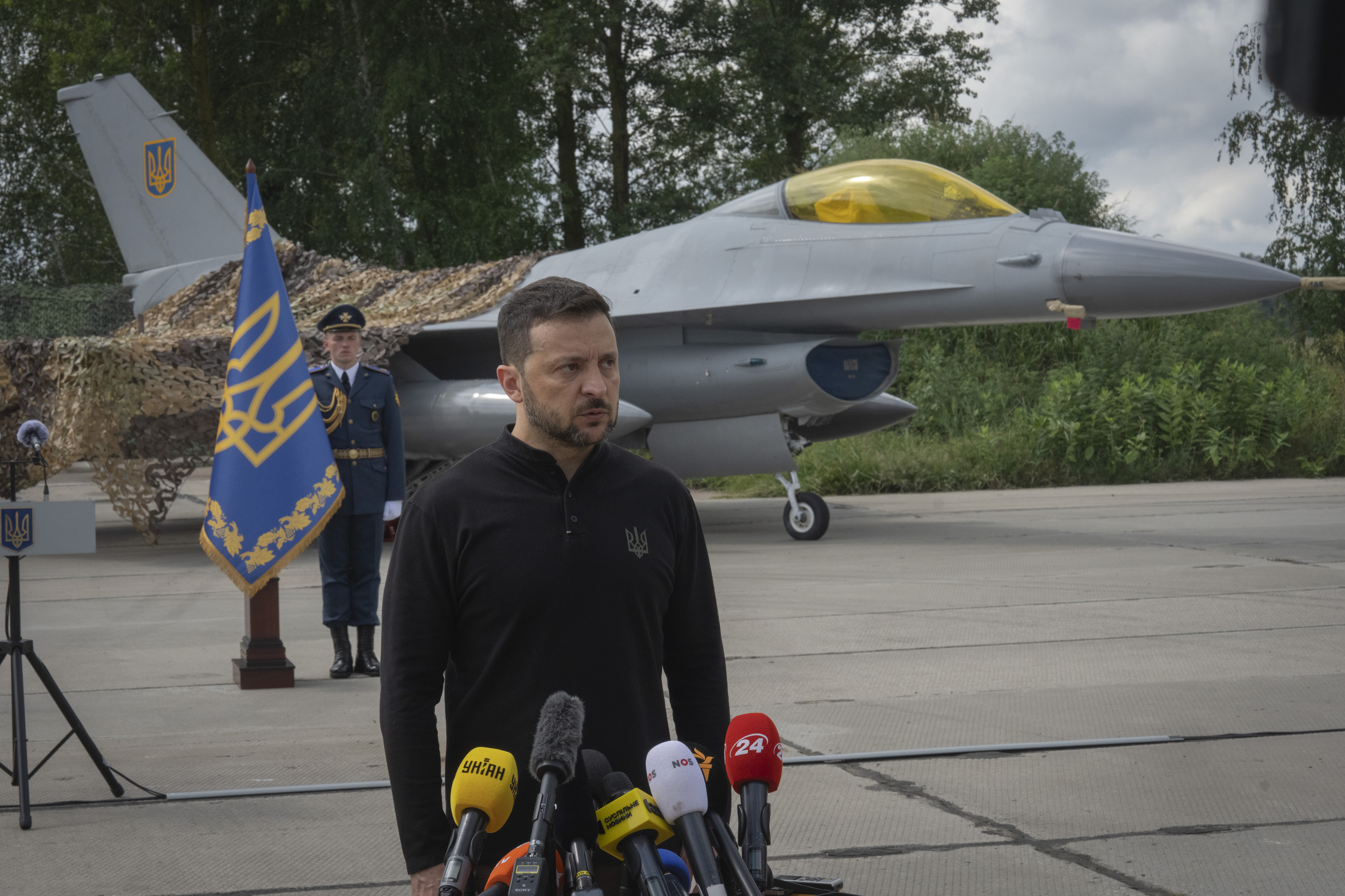 Ukraine's President Volodymyr Zelenskyy talks on the occasion of the Air Forces Day standing against the background of Ukraine's Air Force's F-16 fighter jets.