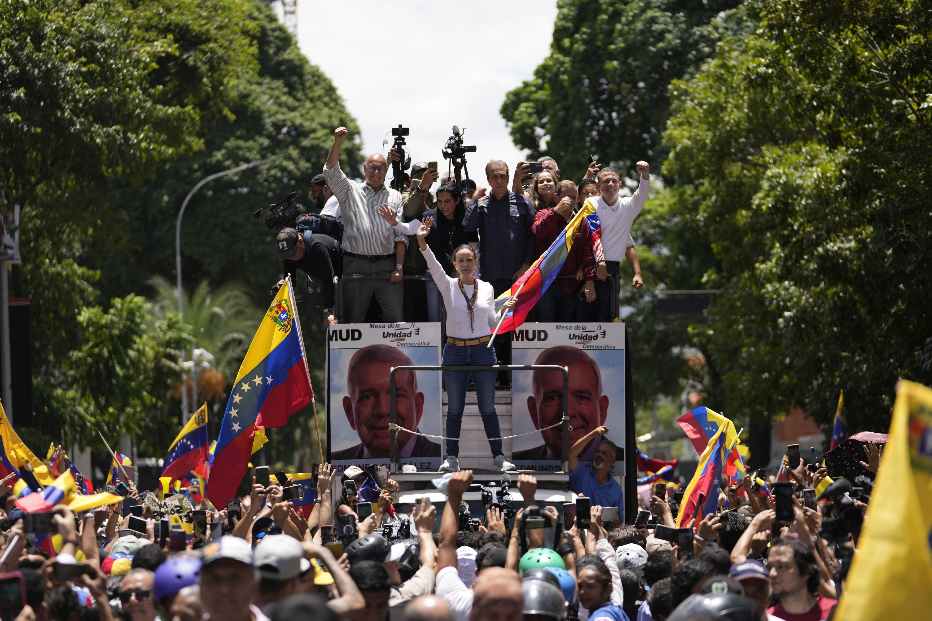 Opposition leader Maria Corina Machado holds a national flag while waving to supporters.