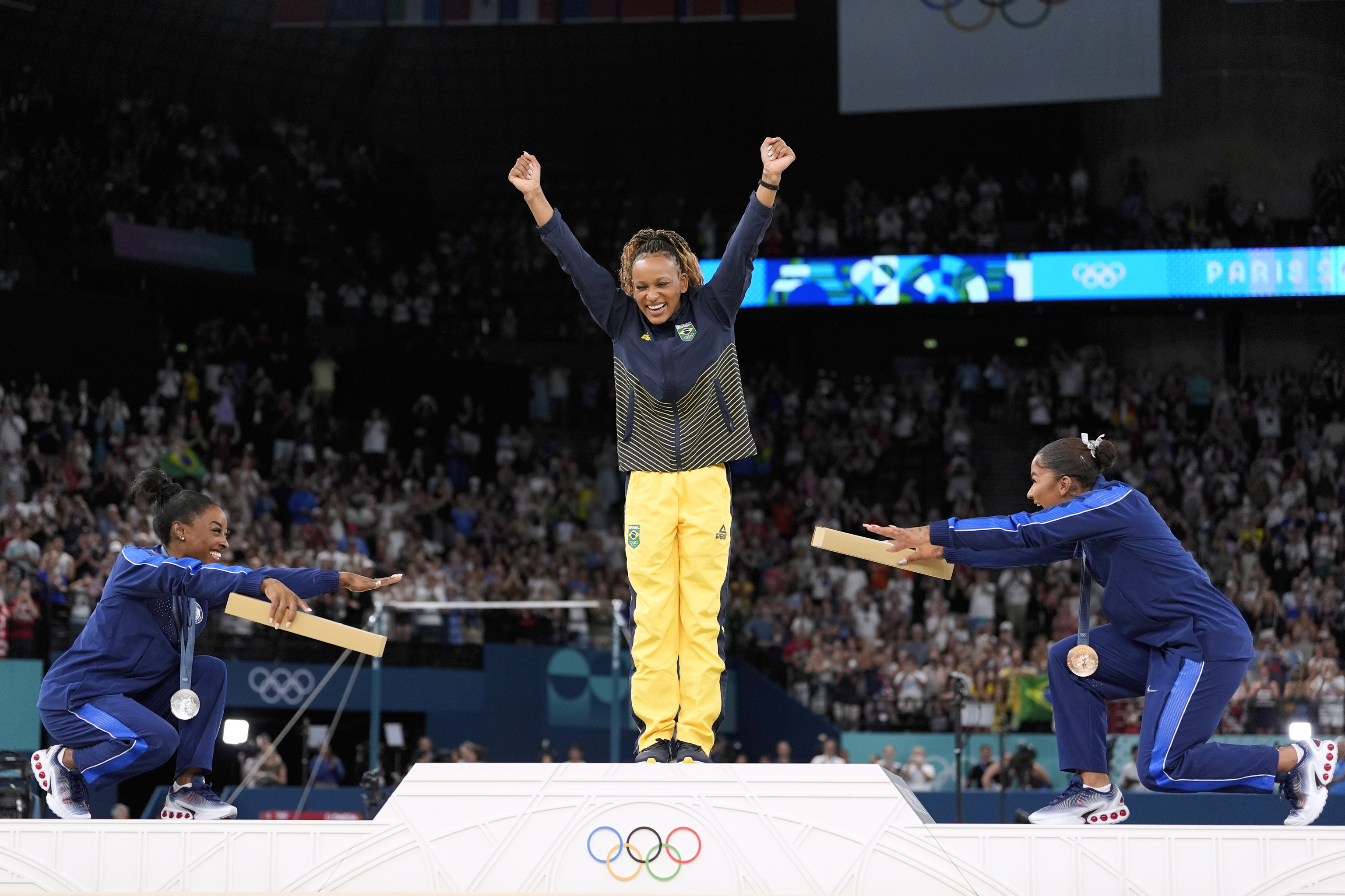 Silver medalist Simone Biles, of the United States, left, and bronze medalist Jordan Chiles, of the United States, right, bow to gold medalist Rebeca Andrade, of Brazil.