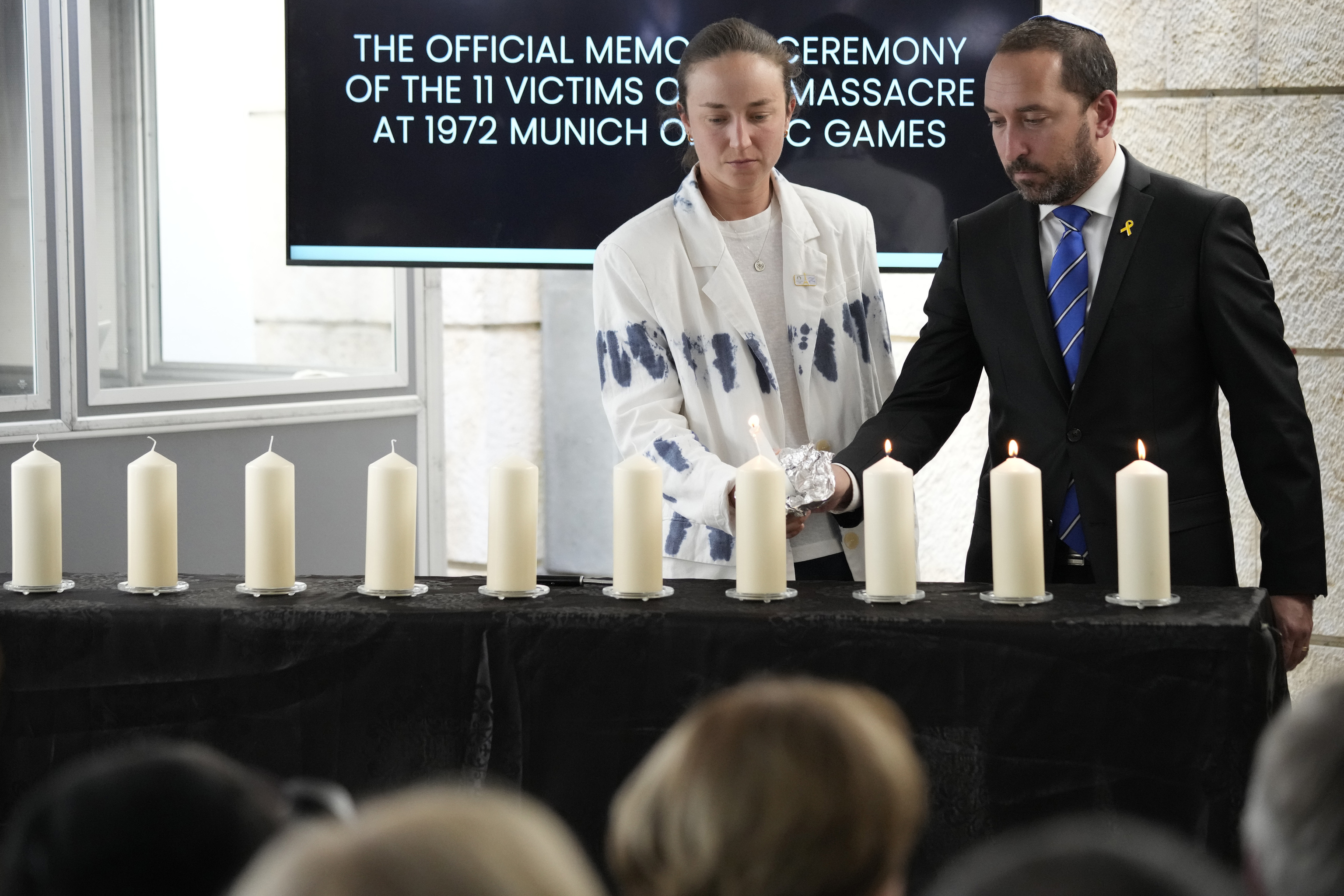 Israeli cyclist Rotem Gafinovitz, center, lights a candle with Israeli diplomat Assaf Moran