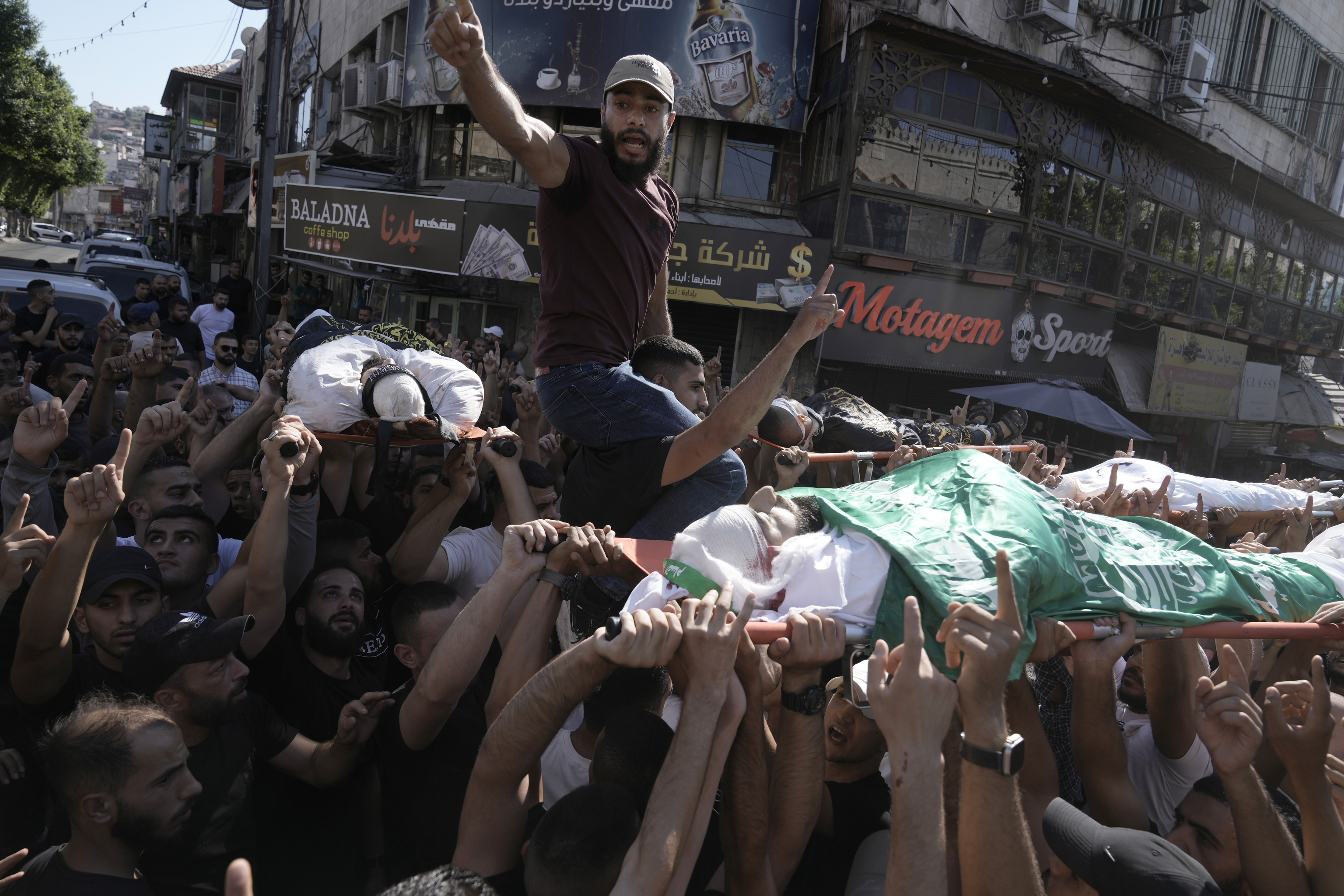 Mourners carry the bodies of five Palestinians during their funeral, draped in flags of the Hamas and Islamic Jihad militant groups