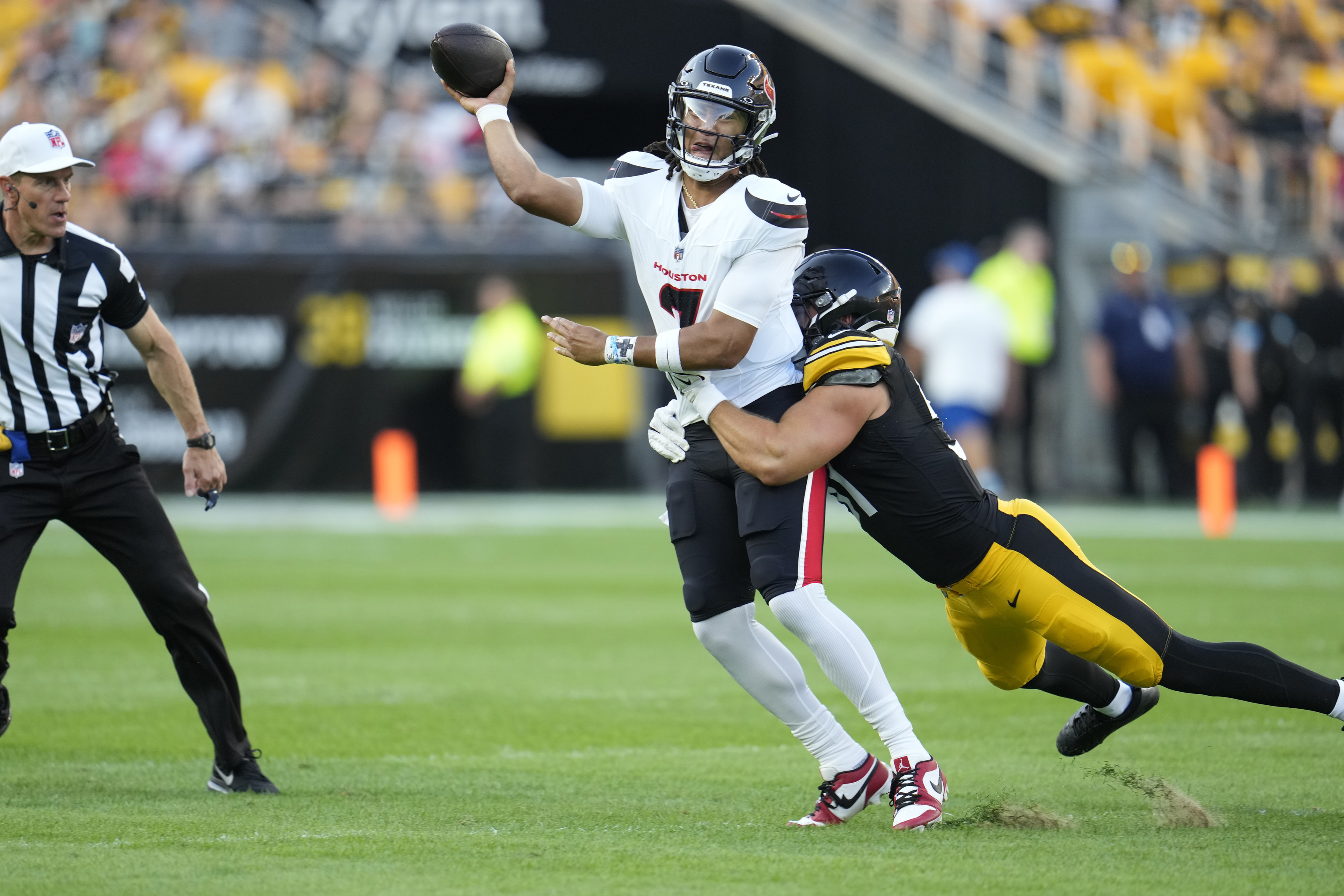 Houston Texans quarterback C.J. Stroud, left, passes while tackled by Pittsburgh Steelers linebacker Nick Herbig.