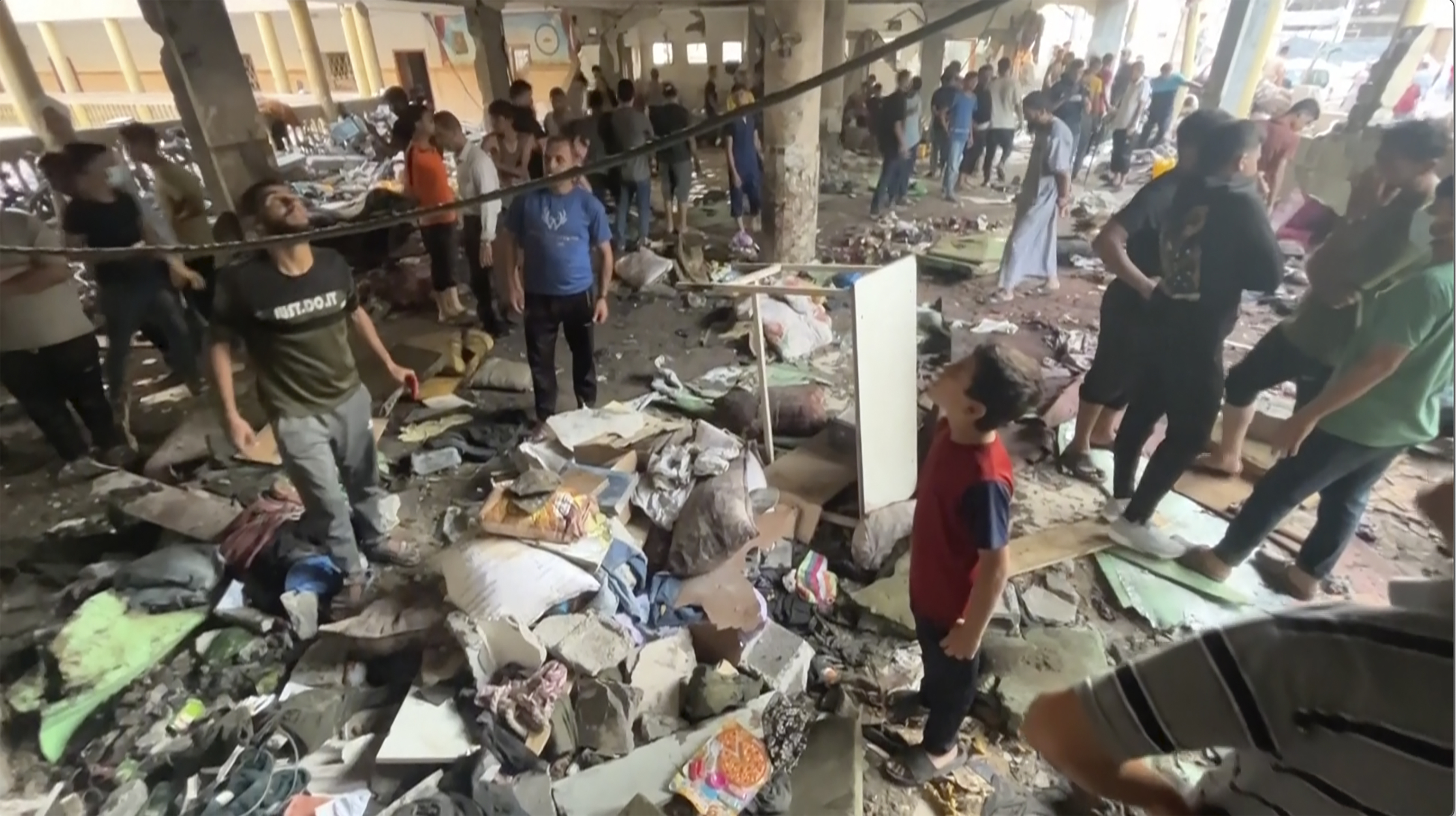 people inspect the dame at a school after being hit by an Israeli airstrike in Gaza City.