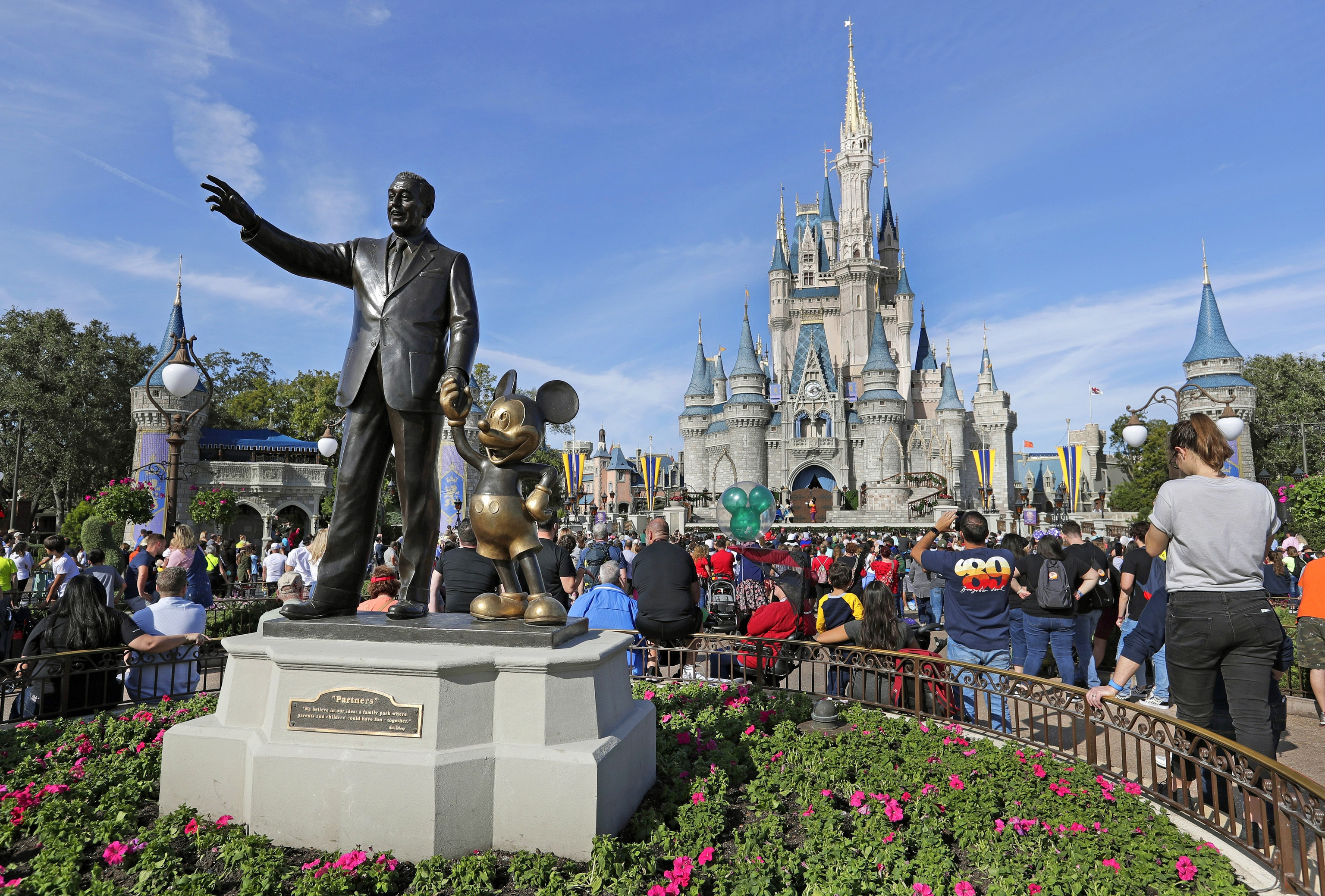 Guests watch a show near a statue of Walt Disney and Micky Mouse.