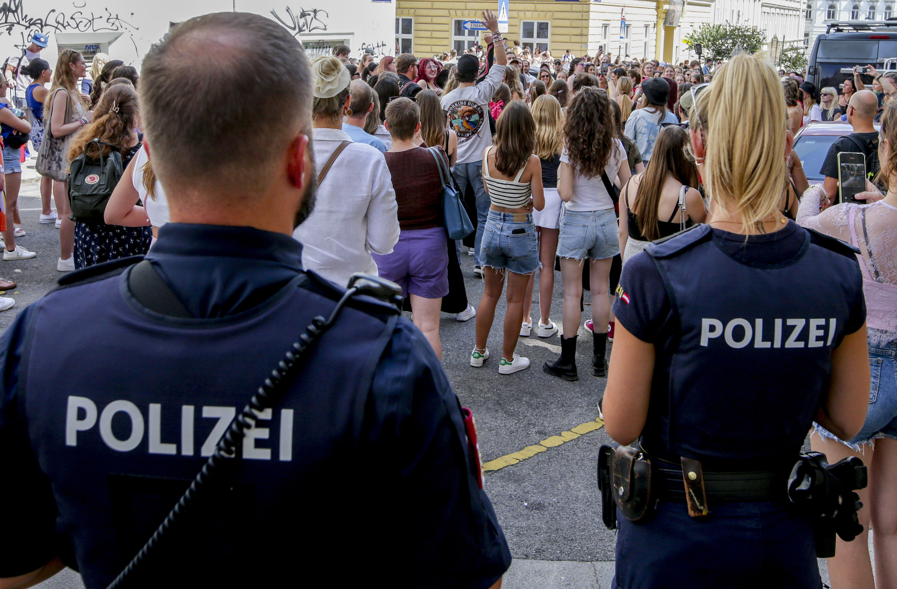 Police officers stand near gathering swifties in Vienna.