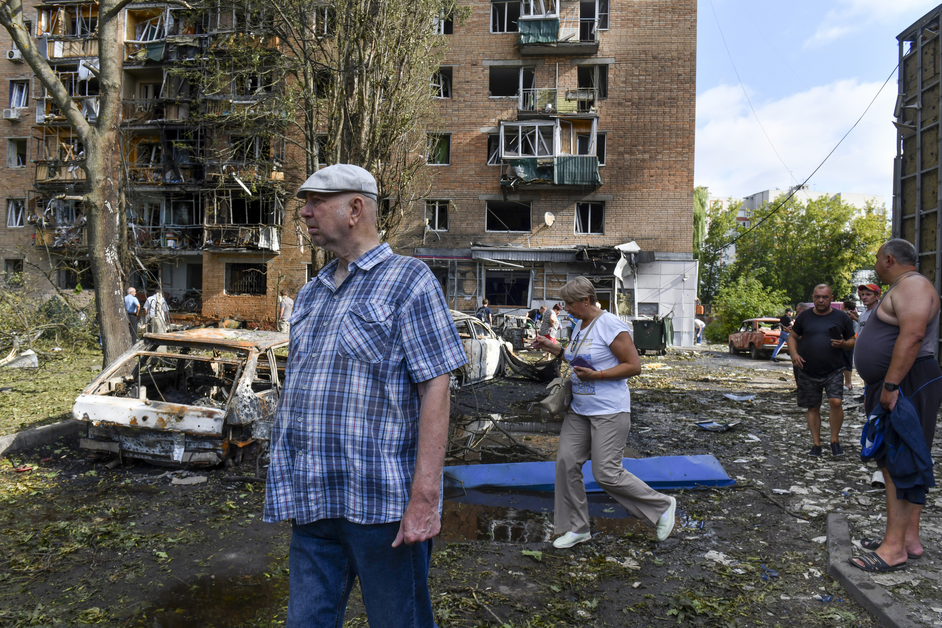 People walk near an apartment building damaged after shelling by the Ukrainian side, in Kursk, Russia