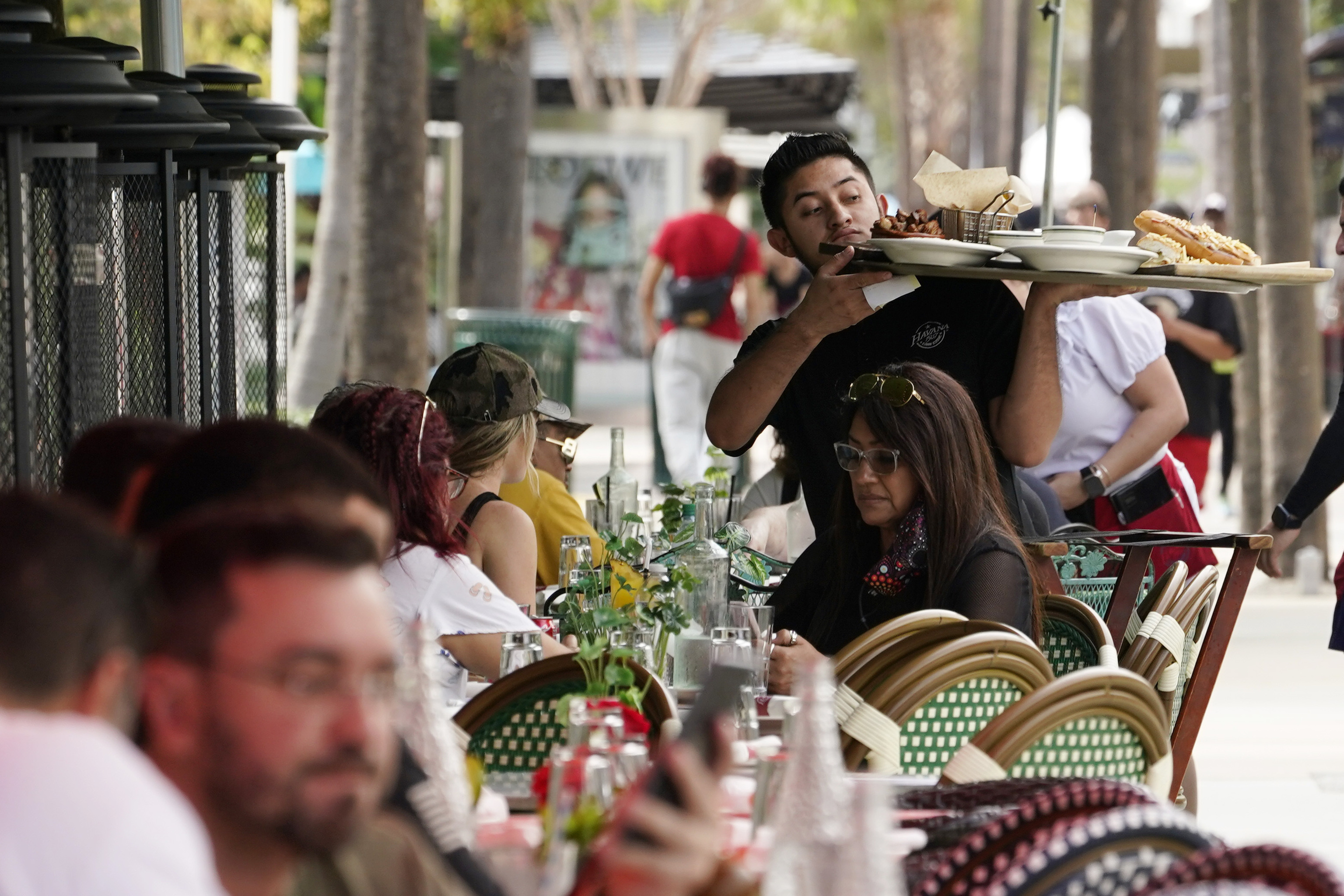 A waiter delivers food to patrons at a restaurant,