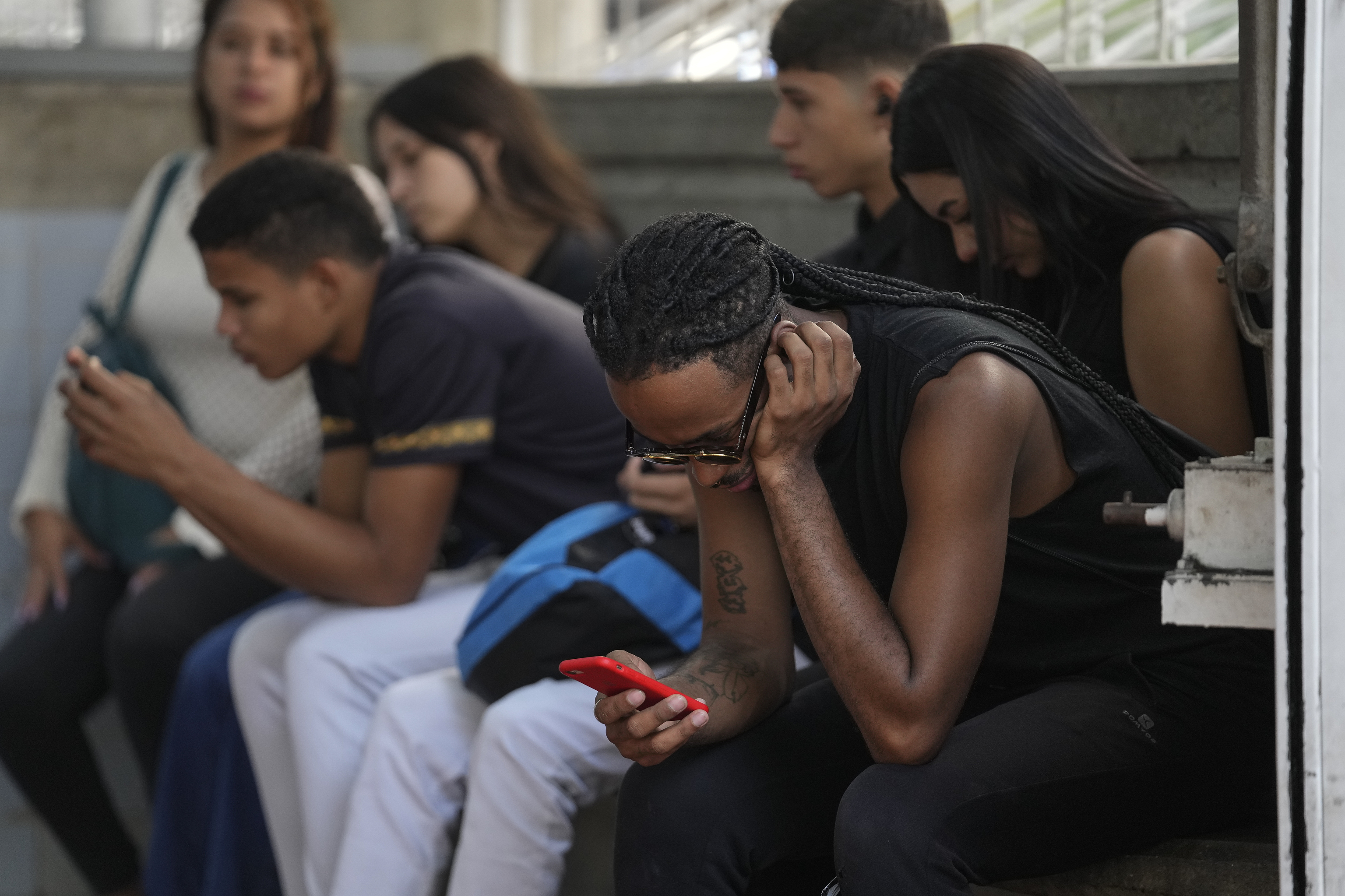 People use their smartphones outside a subway station in Caracas