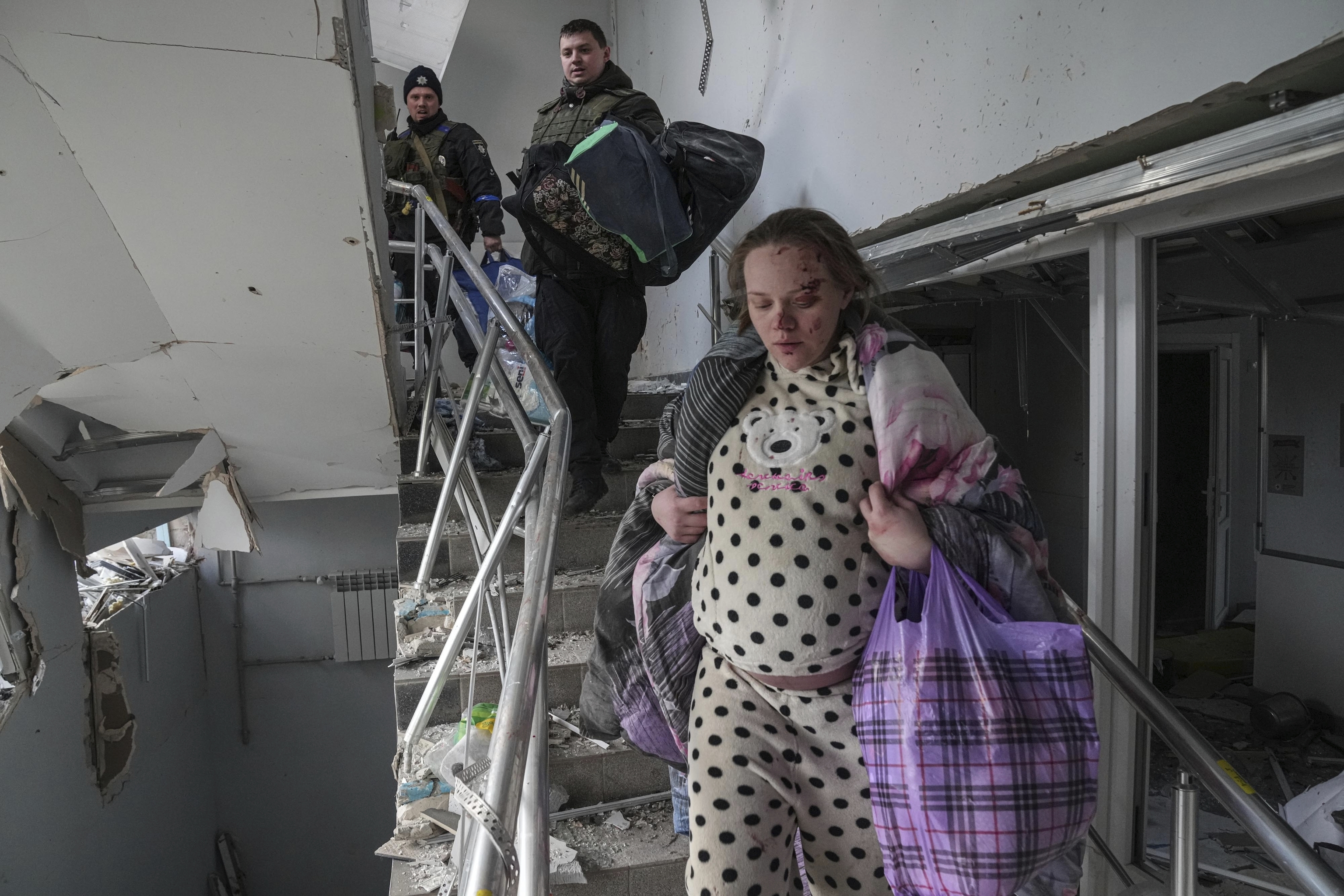 An injured pregnant woman walks downstairs in the damaged by shelling maternity hospital in Mariupol, Ukraine,