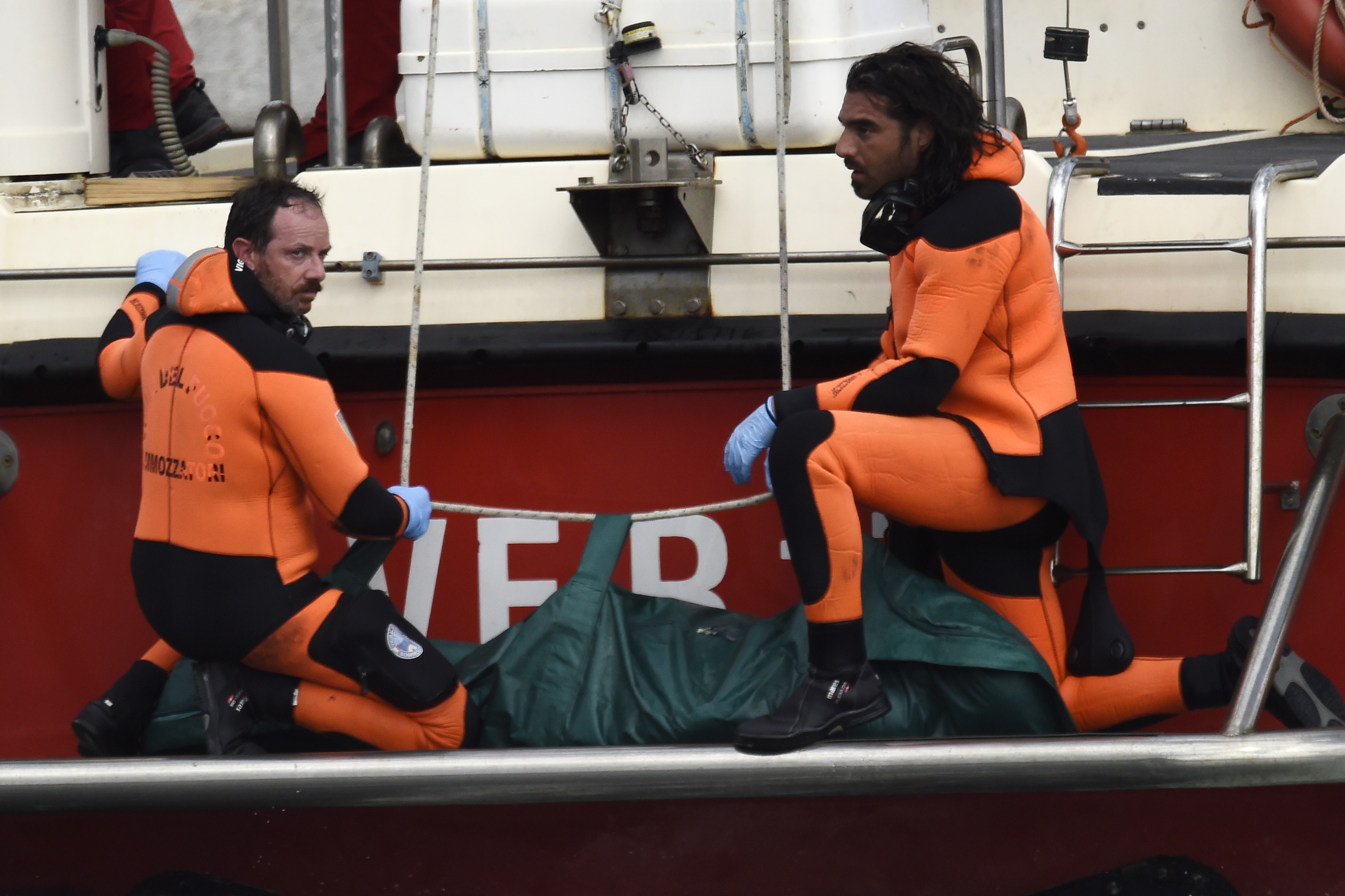 Italian firefighter scuba divers bring ashore, in the green bag, the body of one of the victims from the British-flagged vessel Bayesian